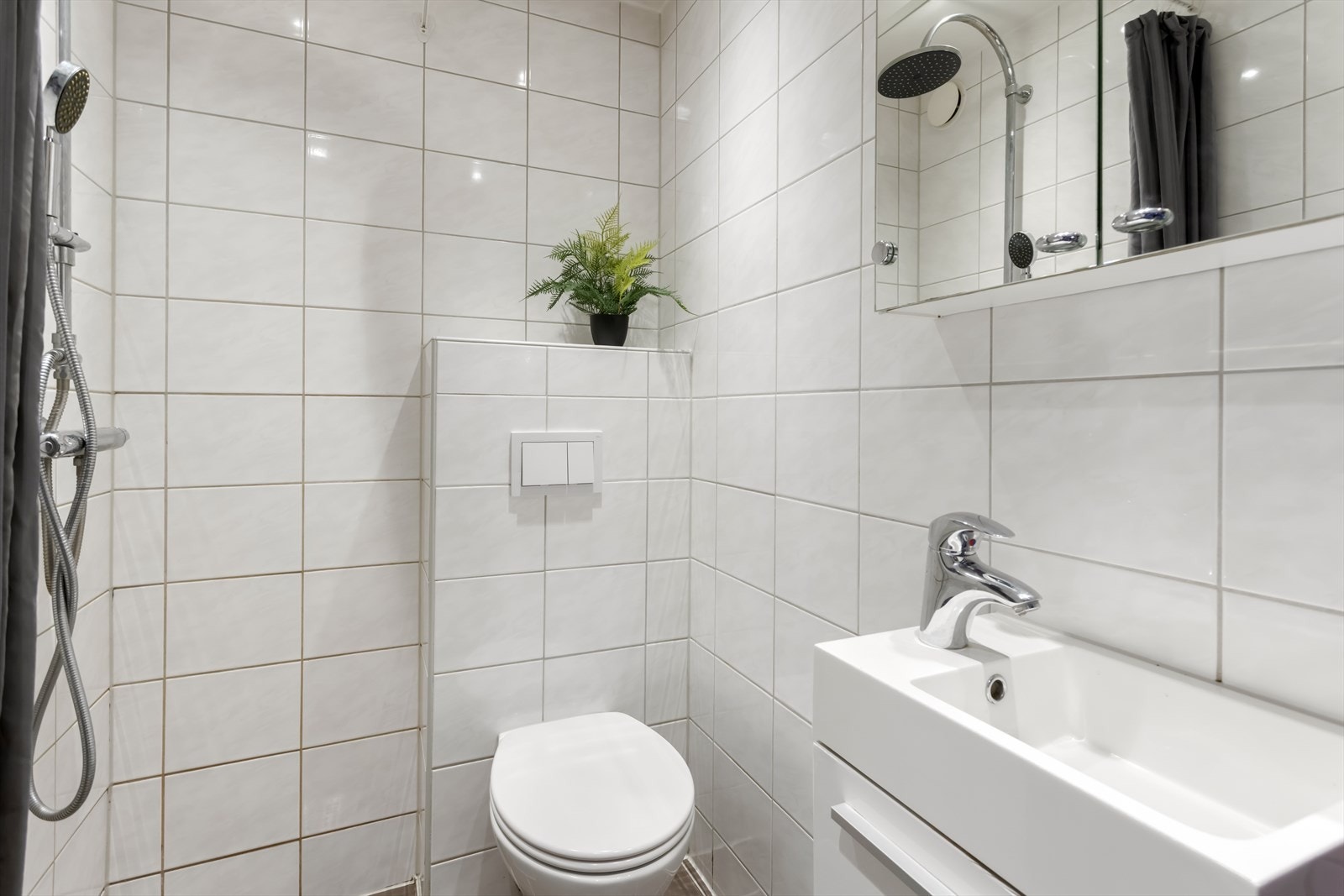 Innredningen består av en servant med underskap, speilskap, vegghengt toalett og en åpen dusjløsning. Galleribilde