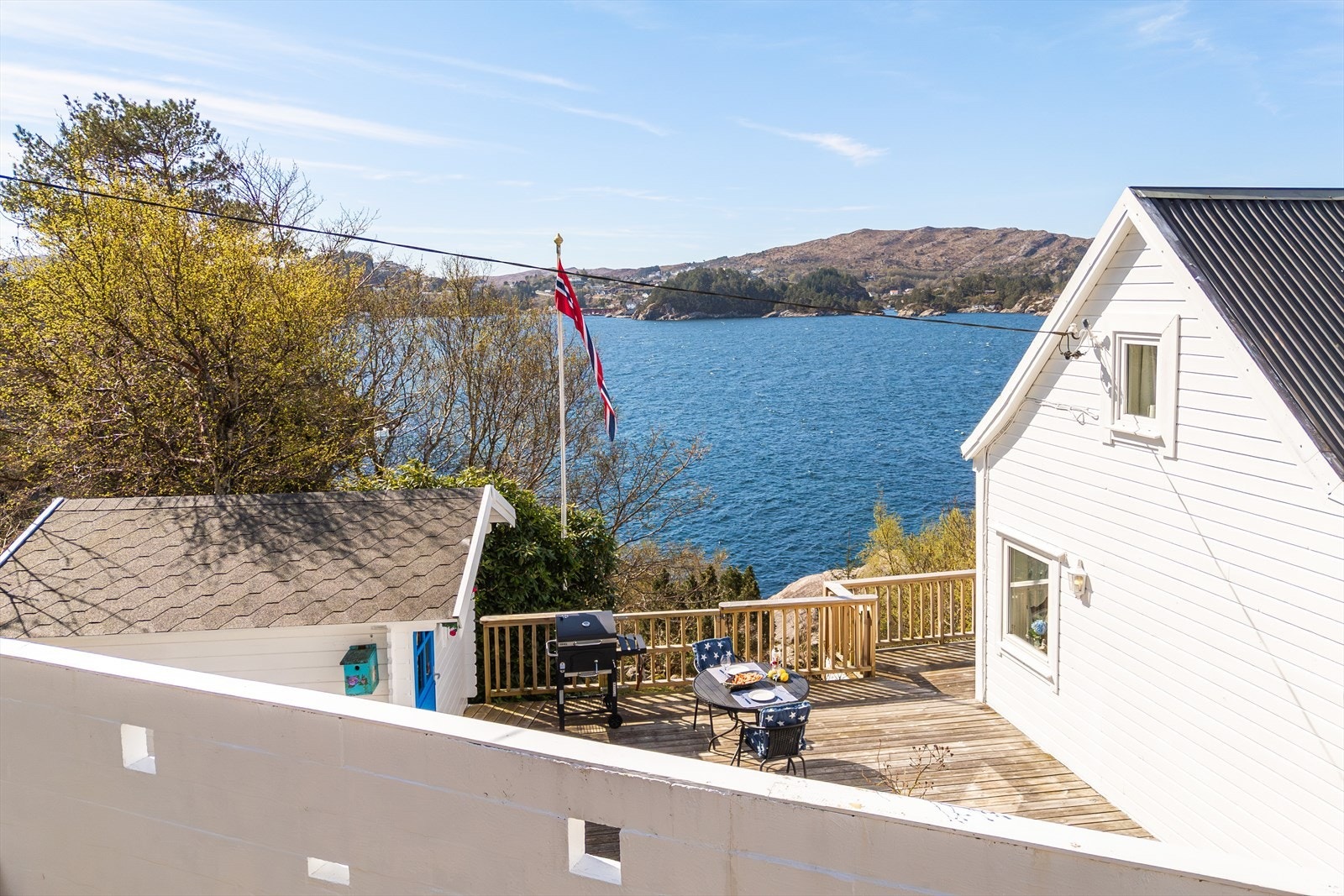 Bilde av terrasse, hytte og utebod tatt på utsiden av leveggen. Galleribilde