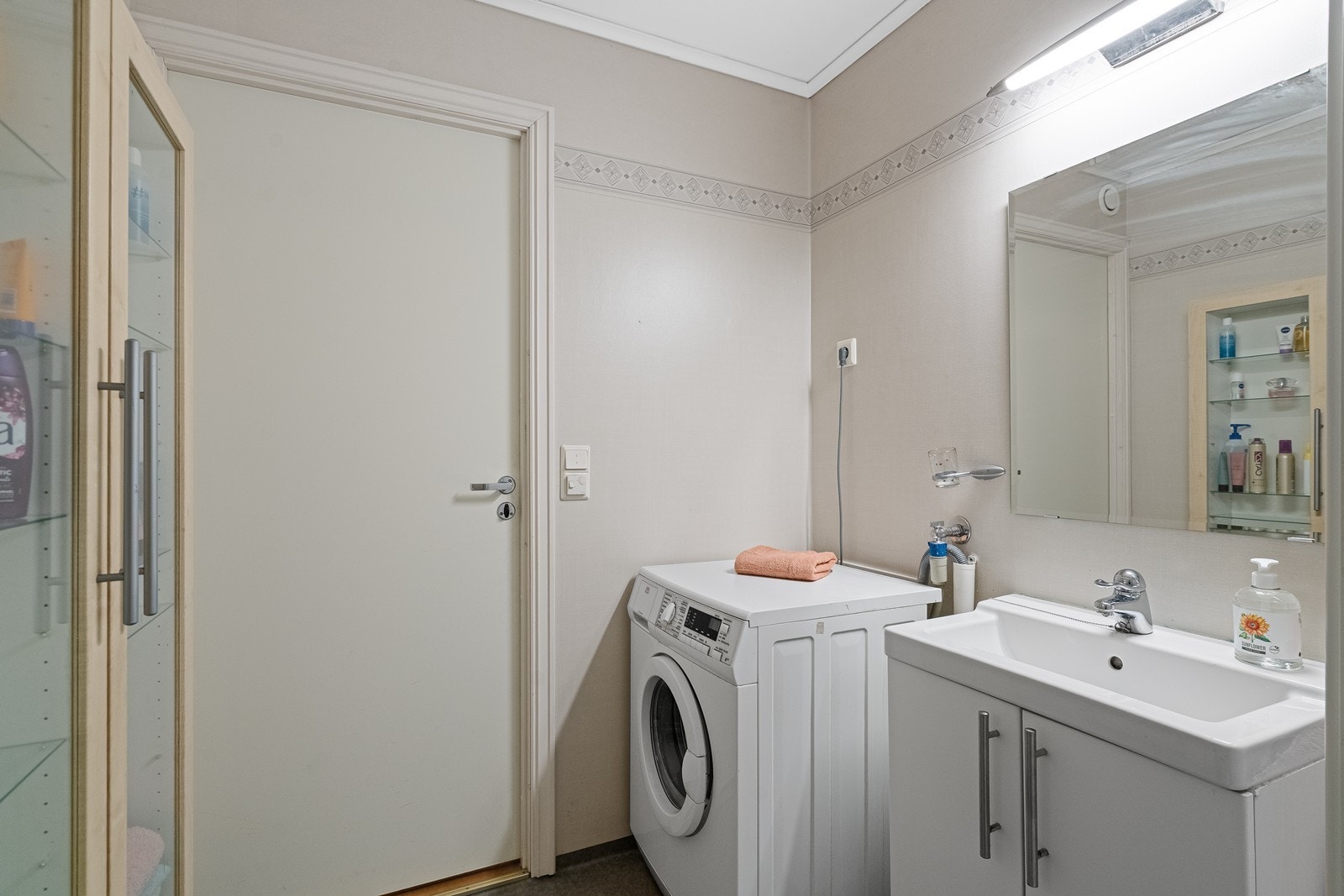 Rommet er innredet med servant nedfelt i baderomsinnredning, toalett og dusjkabinett. Det er også opplegg for vaskemaskin, som gir en praktisk løsning for vask i egen bolig. Badet fremstår funksjonelt og lettstelt. Galleribilde