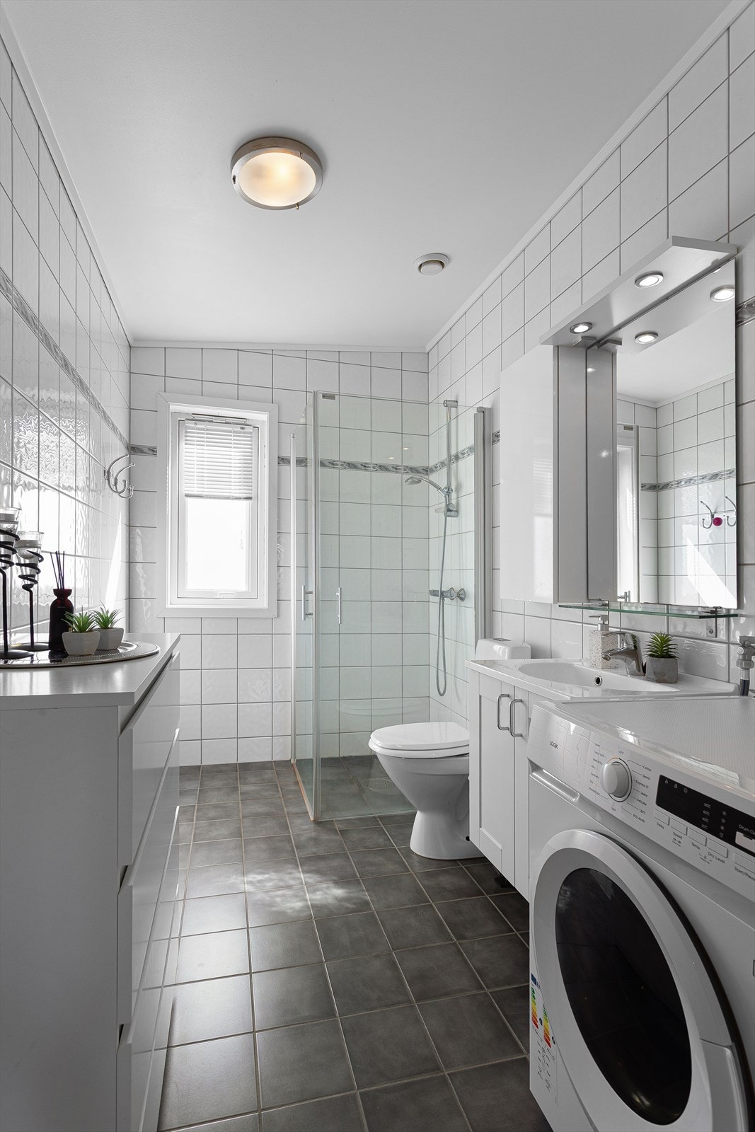 Badet har flislagt gulv med behagelig gulvvarme, dusjhjørne med dører og opplegg for vaskemaskin. Galleribilde