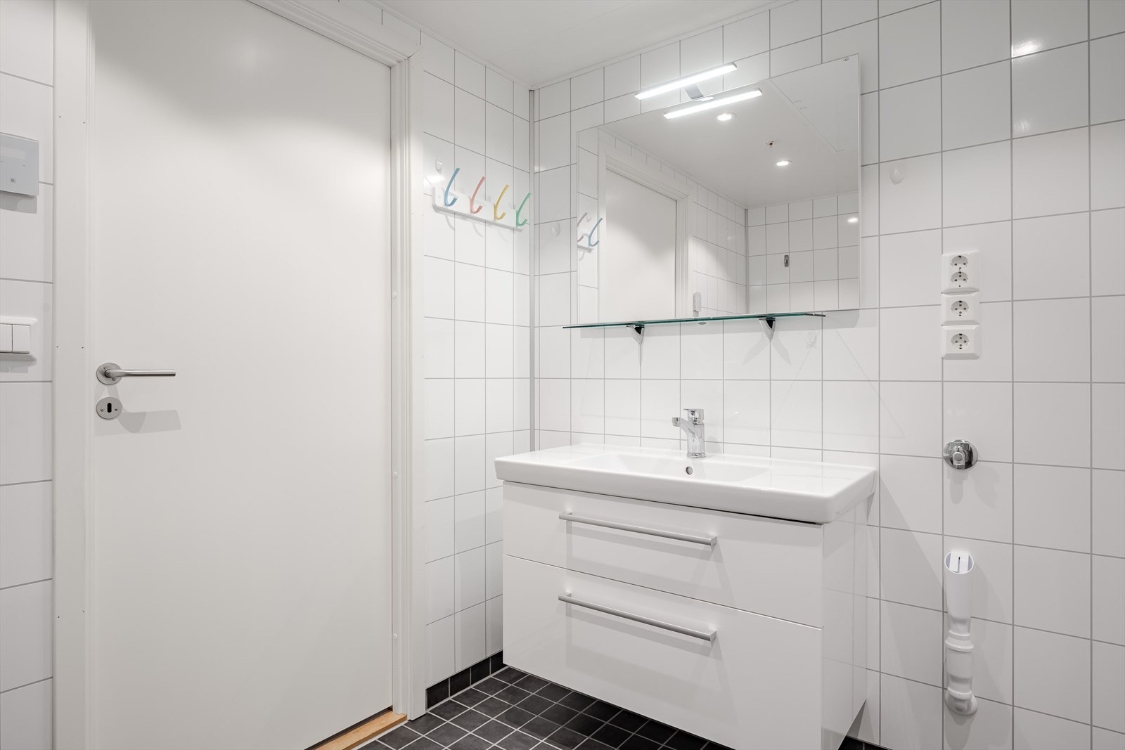 Servantinnredning med glatte fronter og opplegg til vaskemaskin ved siden av. Galleribilde