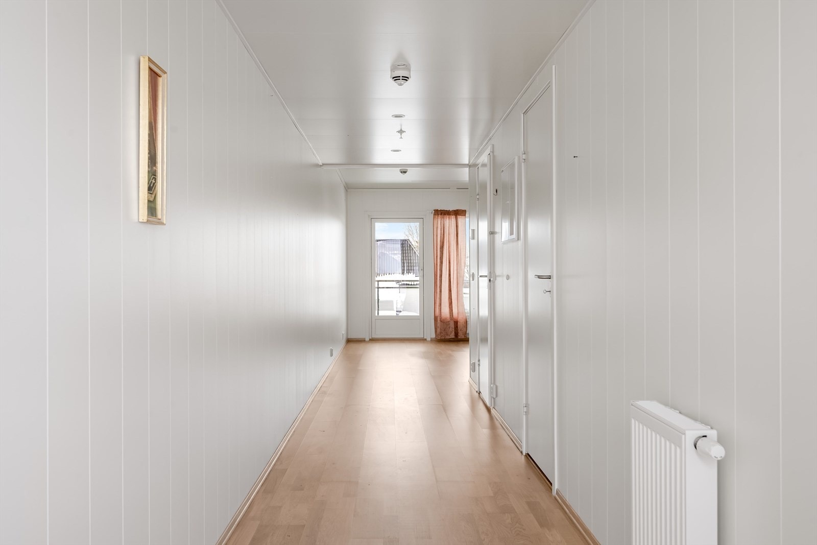 Lys gang med parkett på gulv og panelvegger. Galleribilde