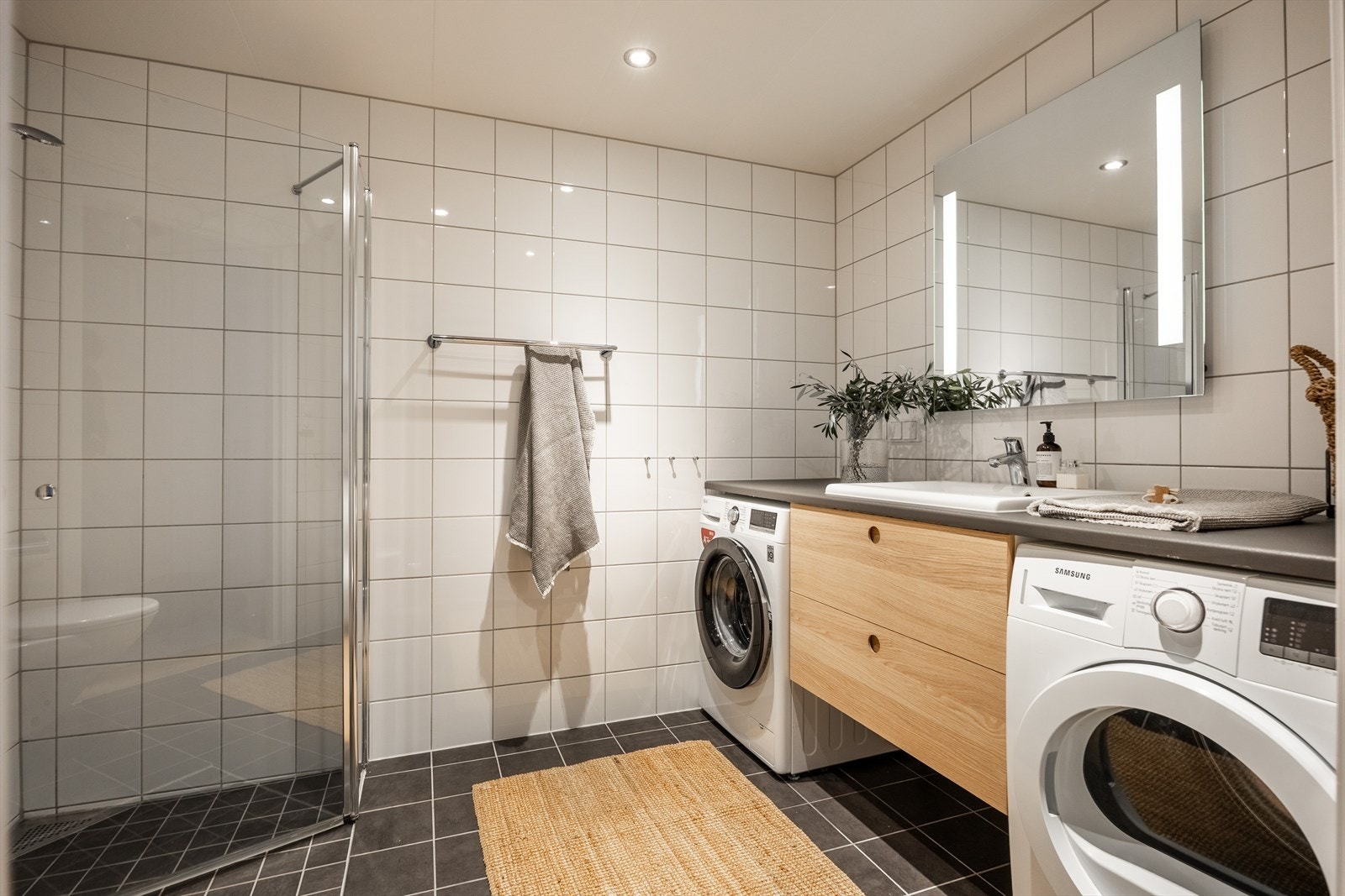 Badet er innredet vegghengt wc, servant m/underskap, speil m/lys, inn-/utadslående dusjdører og opplegg for vaskemaskin. Galleribilde
