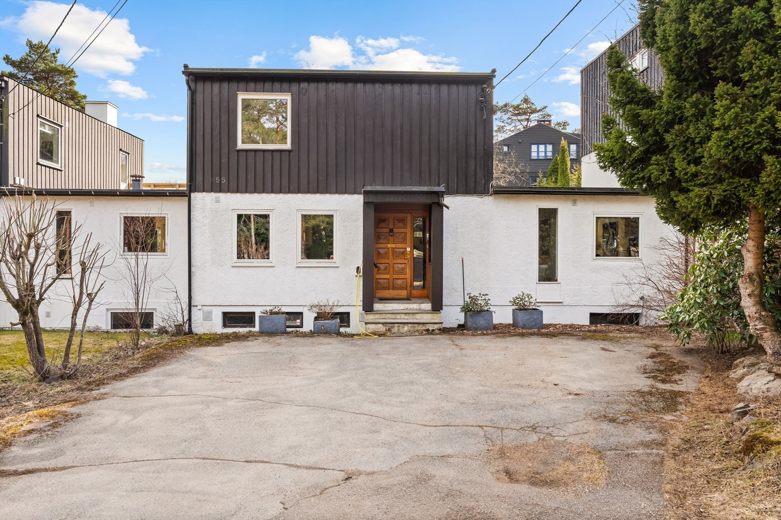 Gårdsplass med biloppstillingsplasser og el-lader montert på husveggen. Galleribilde