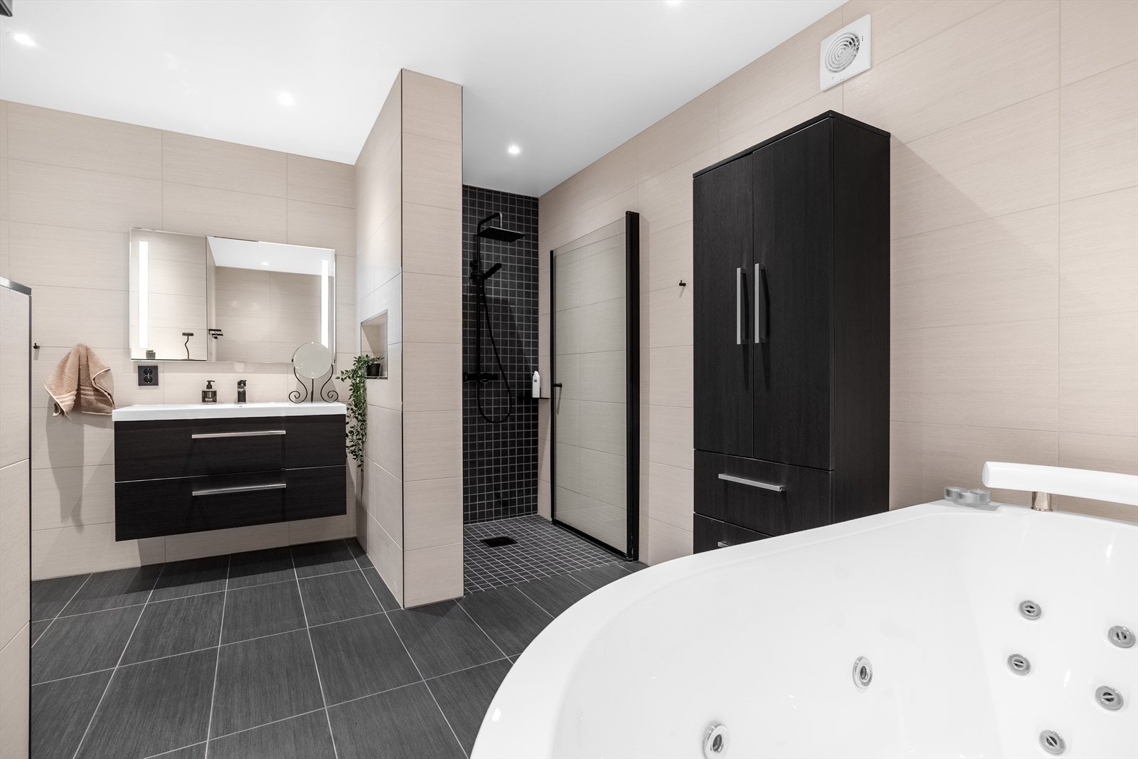 Badet har flislagte overflater, veggmontert toalett og innredning med nedfelt servant. Galleribilde