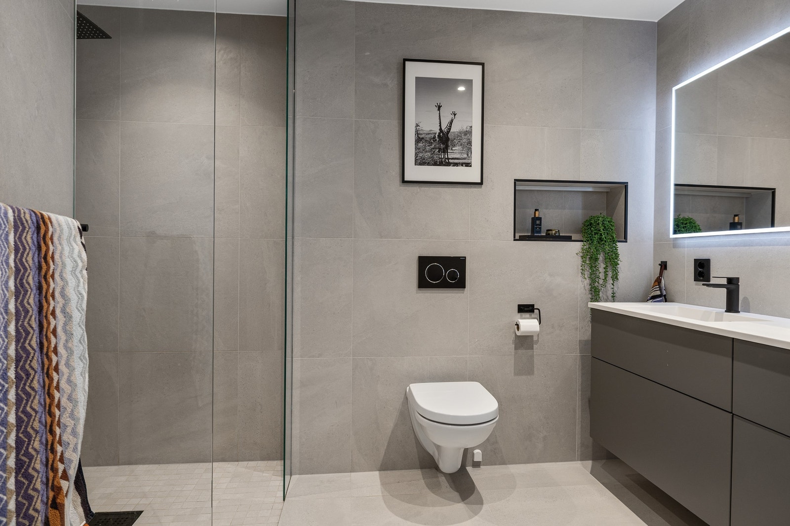 Badet har store fine fliser, varmekabler i gulv og dusjløsning med glassvegger Galleribilde