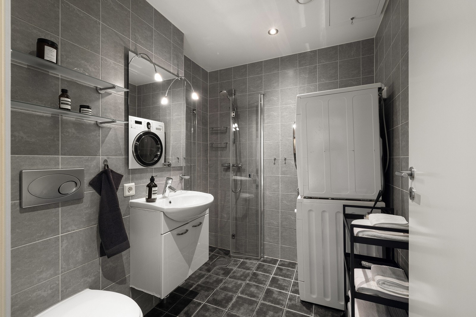 Badet er flislagt og innredet med servant, speil, toalett og dusjsone Galleribilde