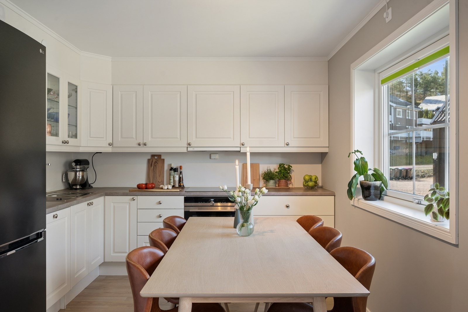 Kjøkkenet er i åpen løsning mot stue med praktisk innredning. Hvite fronter, enkelte glassfronter og benkeplate av laminat. Galleribilde