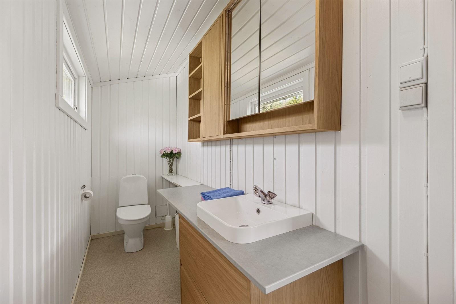 Badet er utstyrt med toalett, servant med underskap og speilskap for oppbevaring. Galleribilde