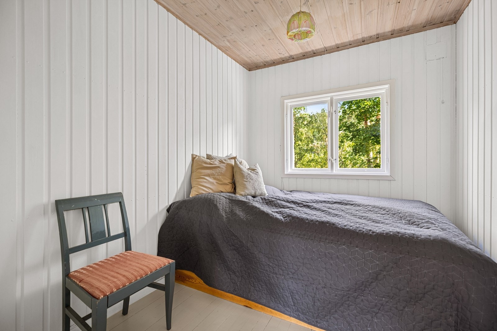 Et av soverommene i hovedhytta, med plass til seng og utsikt mot skogen- her er det plass til familiekøye. Galleribilde