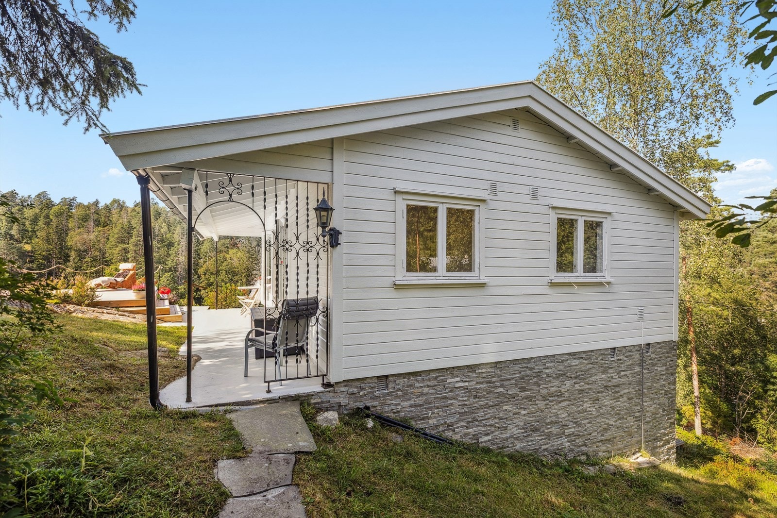 Eiet tomt som hovedsakelig er en naturtomt med sti og trappeadkomst til bygningene. Galleribilde