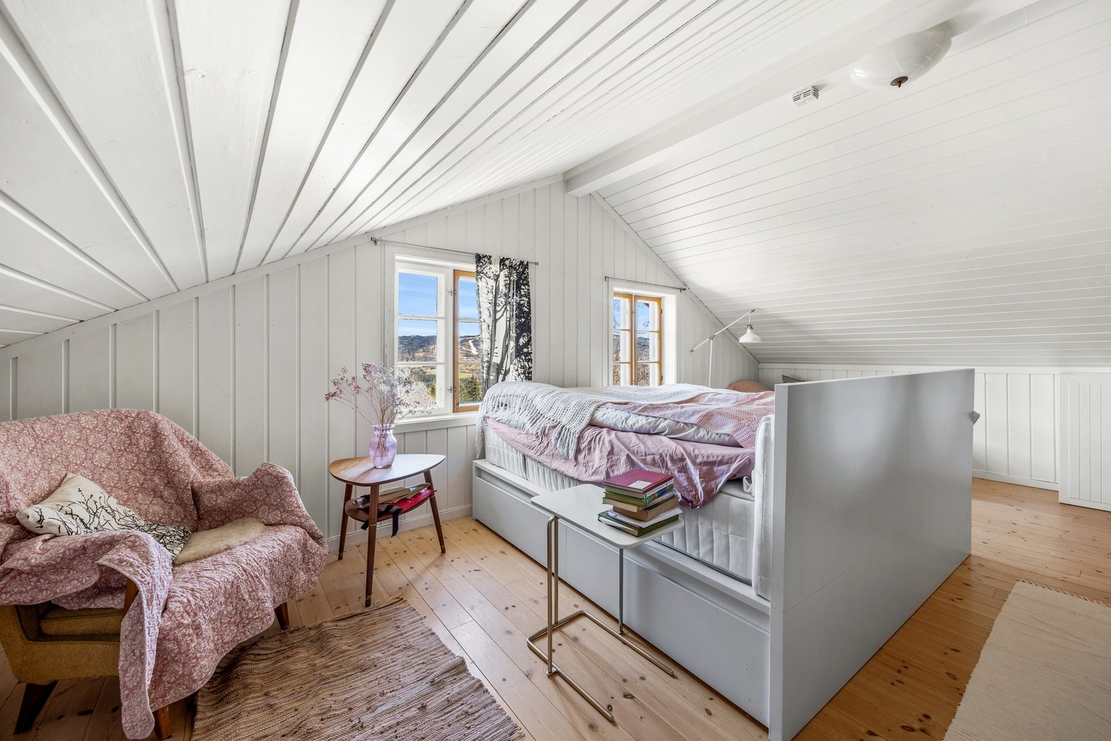 Hovedsoverommet fremstår som innbydende med malte panelvegger, sjarmerende skråtak og originale heltre gulvbord. Galleribilde