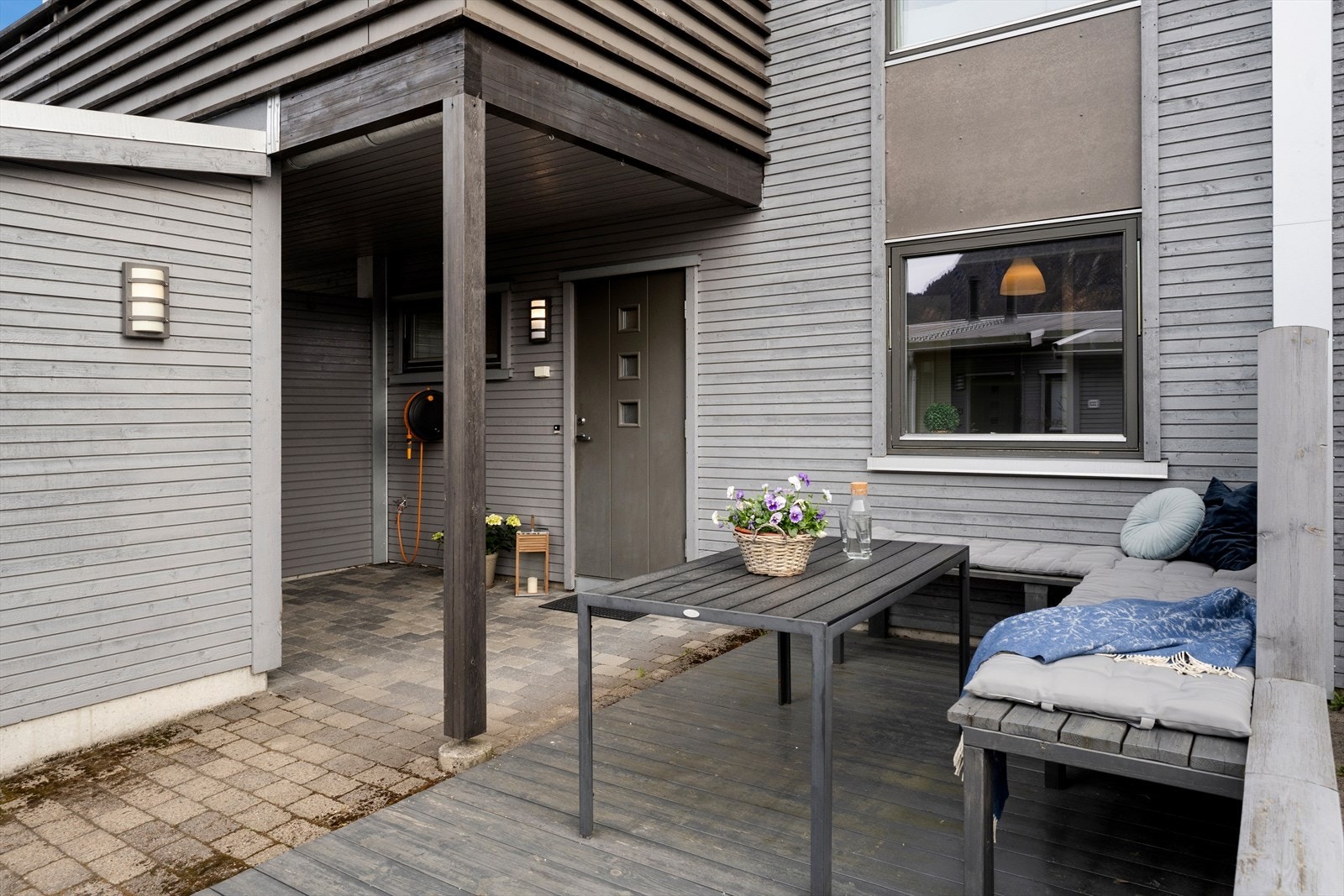 Tiltalende inngangsparti med belegningsstein og treplatting med plass til utemøblement. Galleribilde