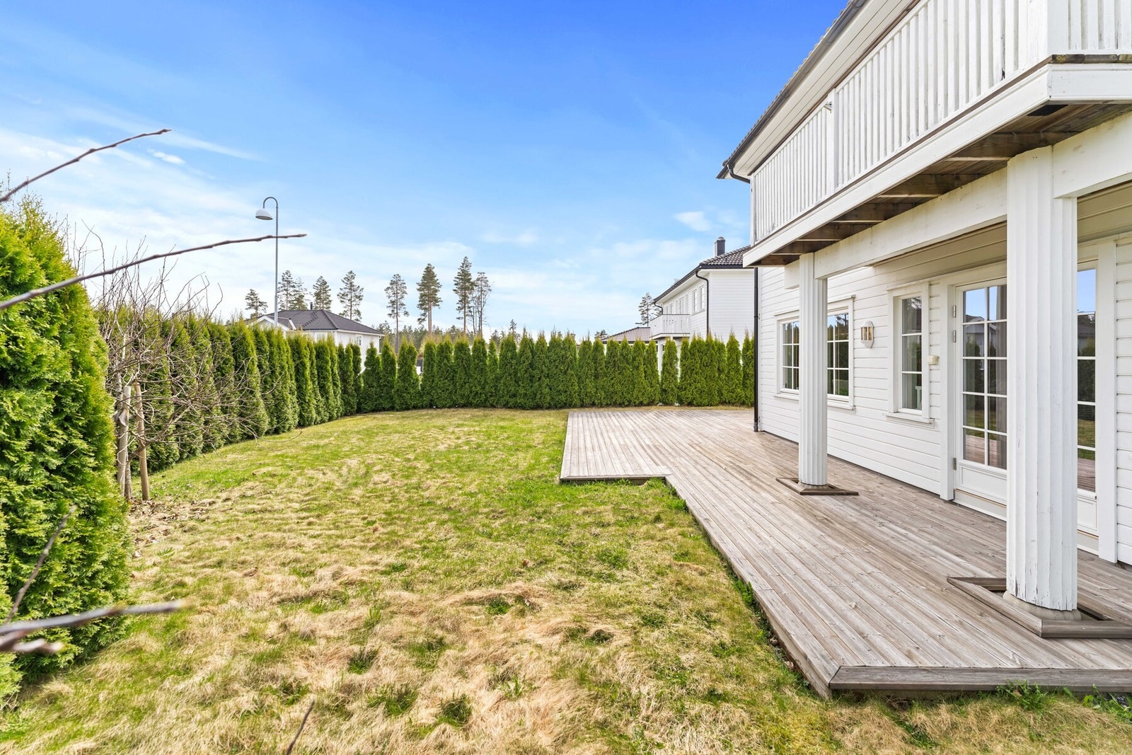 Stor terrasse og skjermet hage med to epletrær og hekk rundt tomten, god plass til utemøbler, lek og sosiale soner. Galleribilde