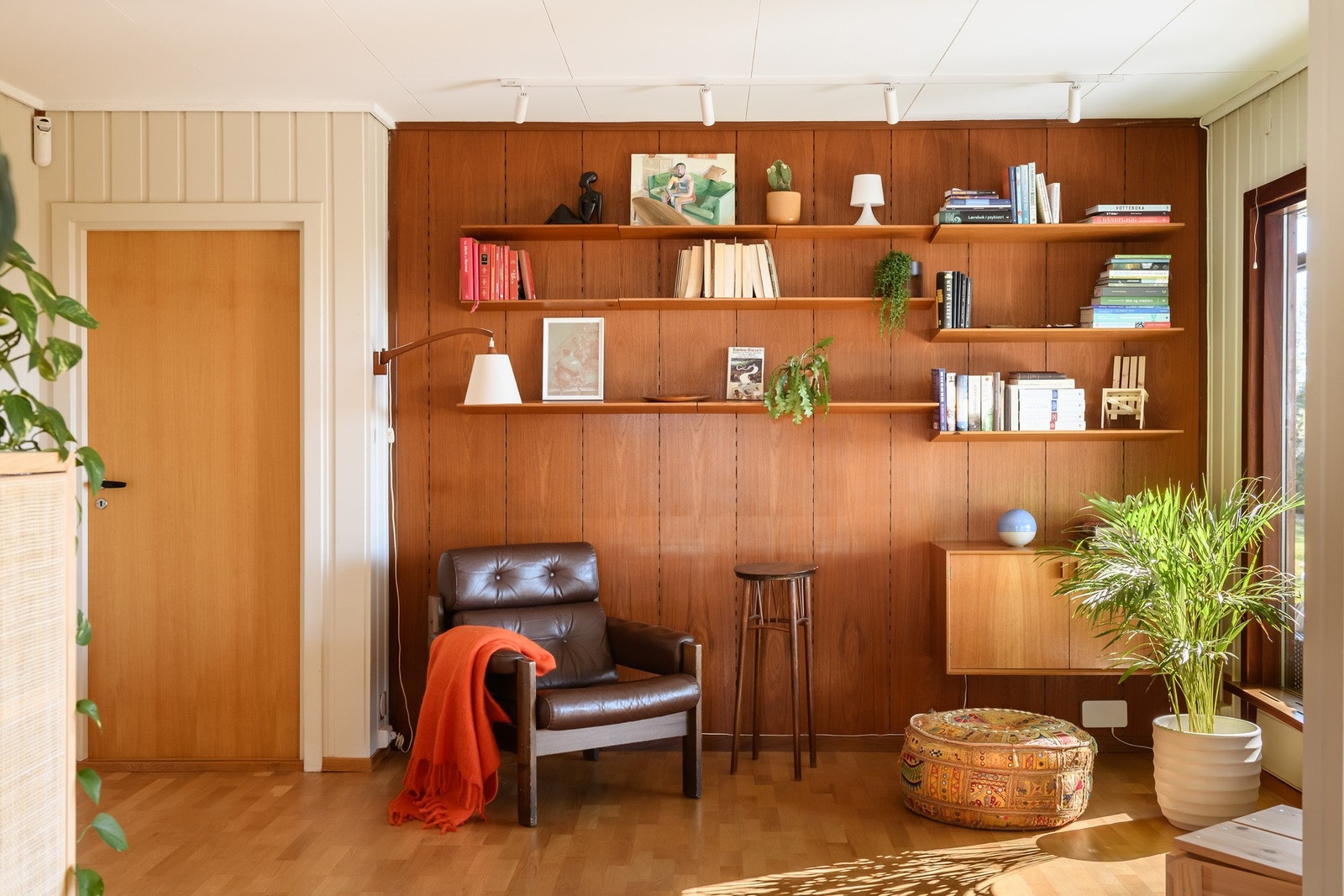 Biblioteksonen har en vegg med originalt teak-panel og plassbygde bokhyller, og har direkte utgang til terrassen. Galleribilde