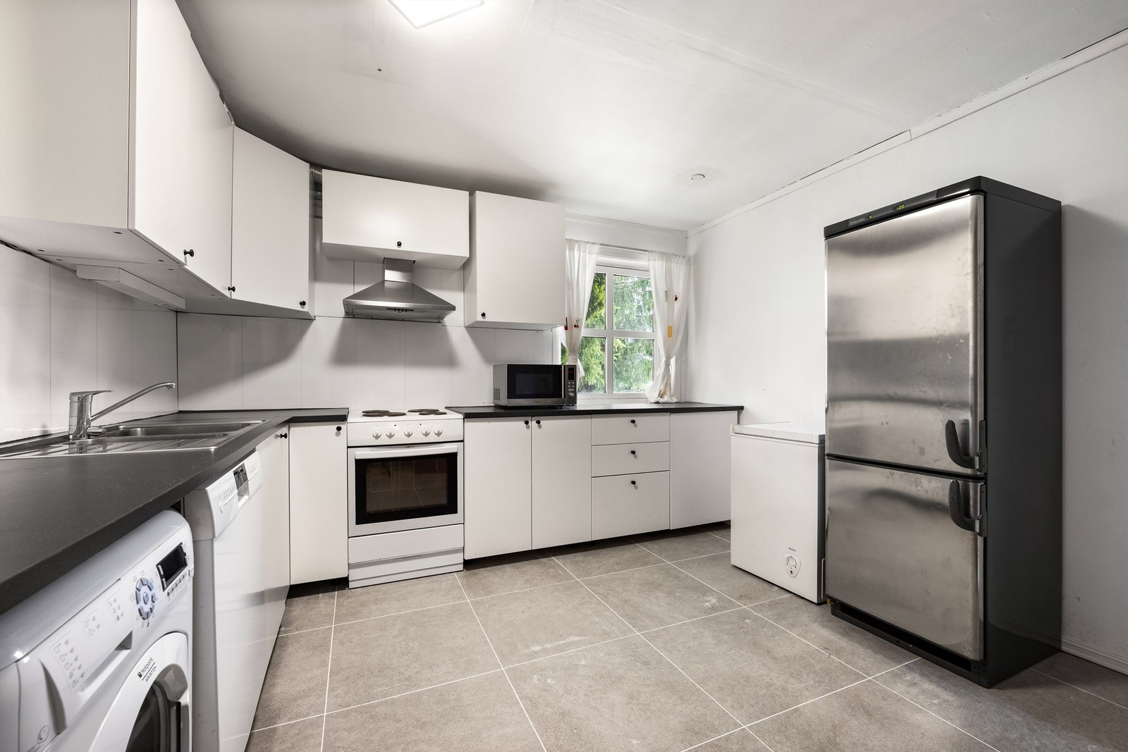 Kjøkkeninnredning med slette fronter fra 2017, benkeplate med laminert flate og nedfelt oppvaskkum i rustfritt stål med ett-greps armatur. Galleribilde