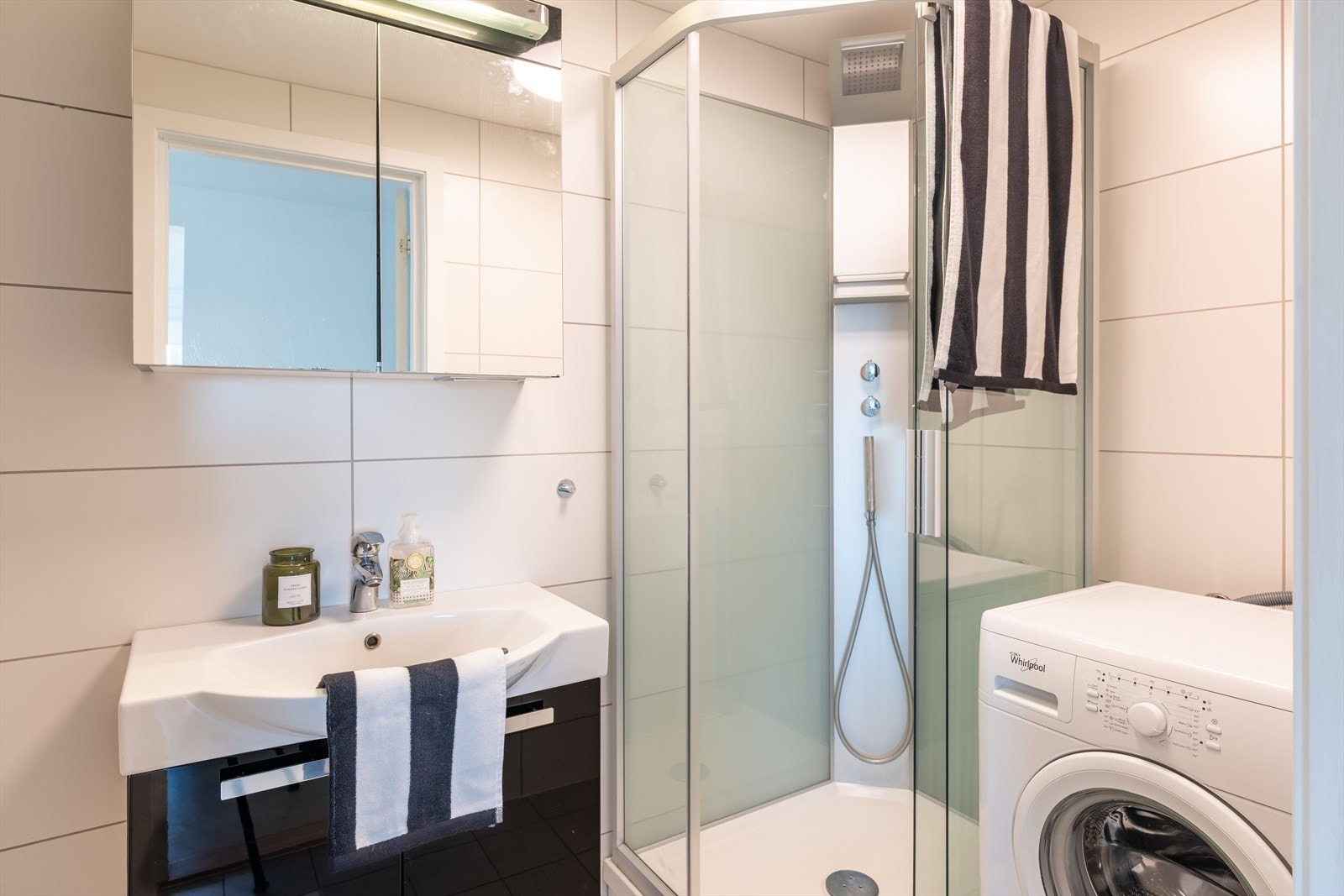 Badet er utstyrt med servant, servantskap, mekanisk avtrekk, opplegg for vaskemaskin, veggmontert wc og dusjkabinett. Galleribilde