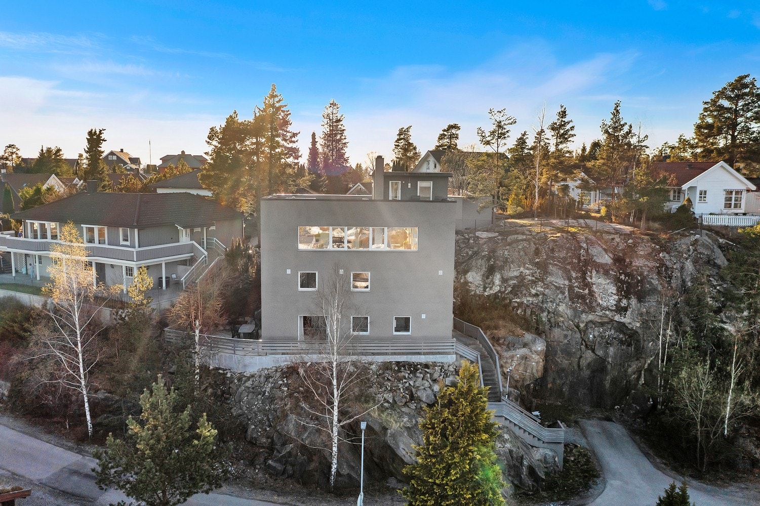 Boligen ligger på en skrånende tomt med fasader av malte, pussede murfasader. Galleribilde