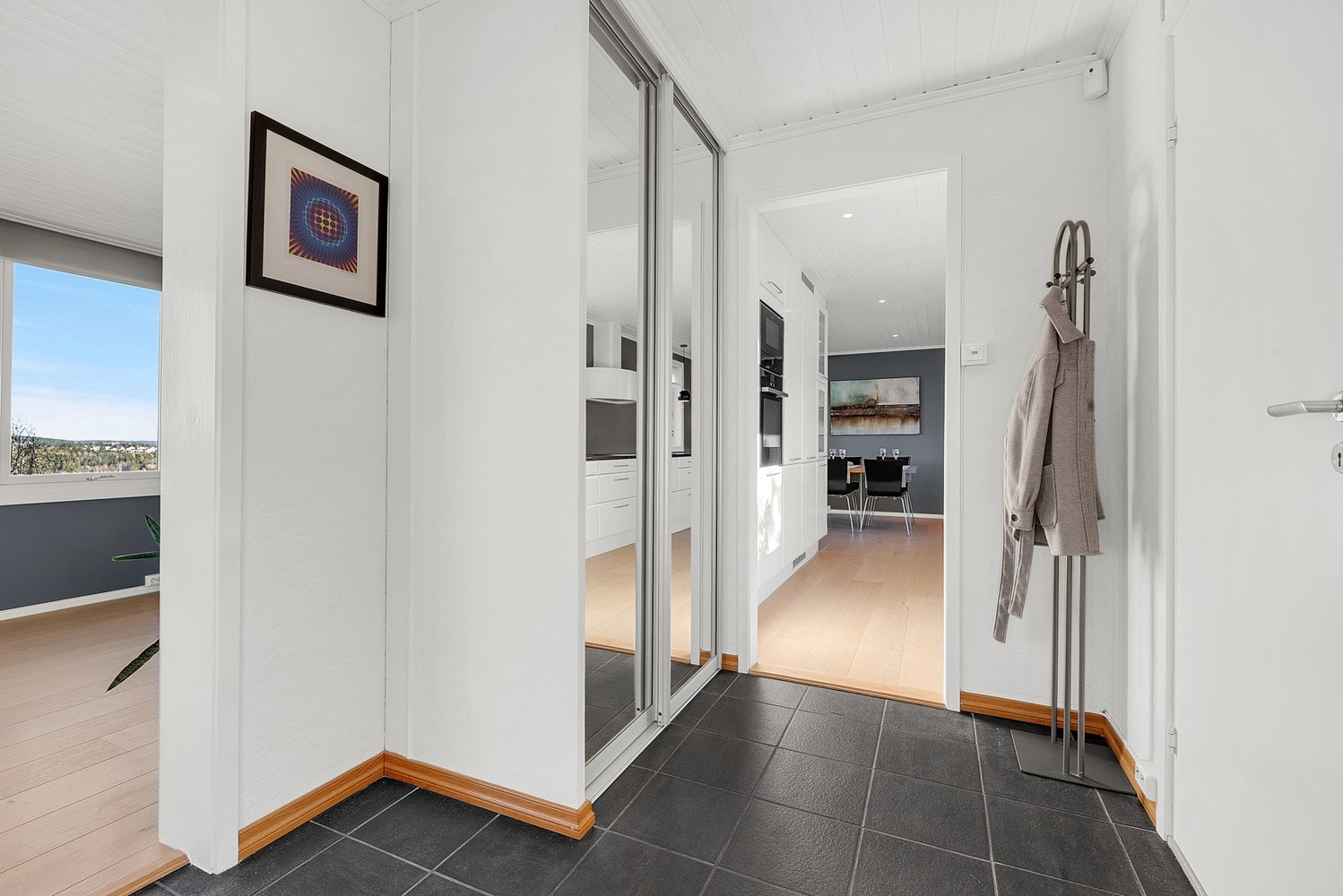 Fra hallen er det direkte tilgang til kjøkkenet og stuen, med god plass til oppbevaring i en skyvedørsgarderobe. Galleribilde