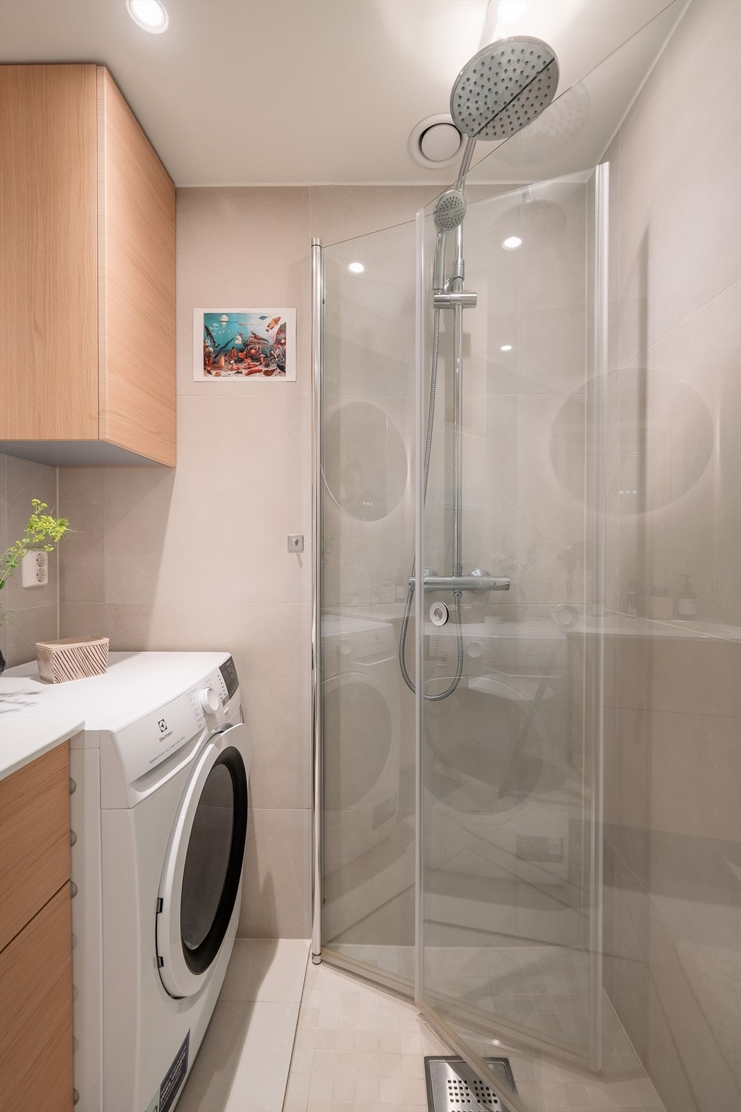 Badet er innredet med lekre fliser med gulvvarme, servantinnredning og speil med lys på vegg, samt vegghengt skap, vegghengt toalett, dusjhjørne med innfellbare glassdører samt opplegg og plass til vaskemaskin. Galleribilde
