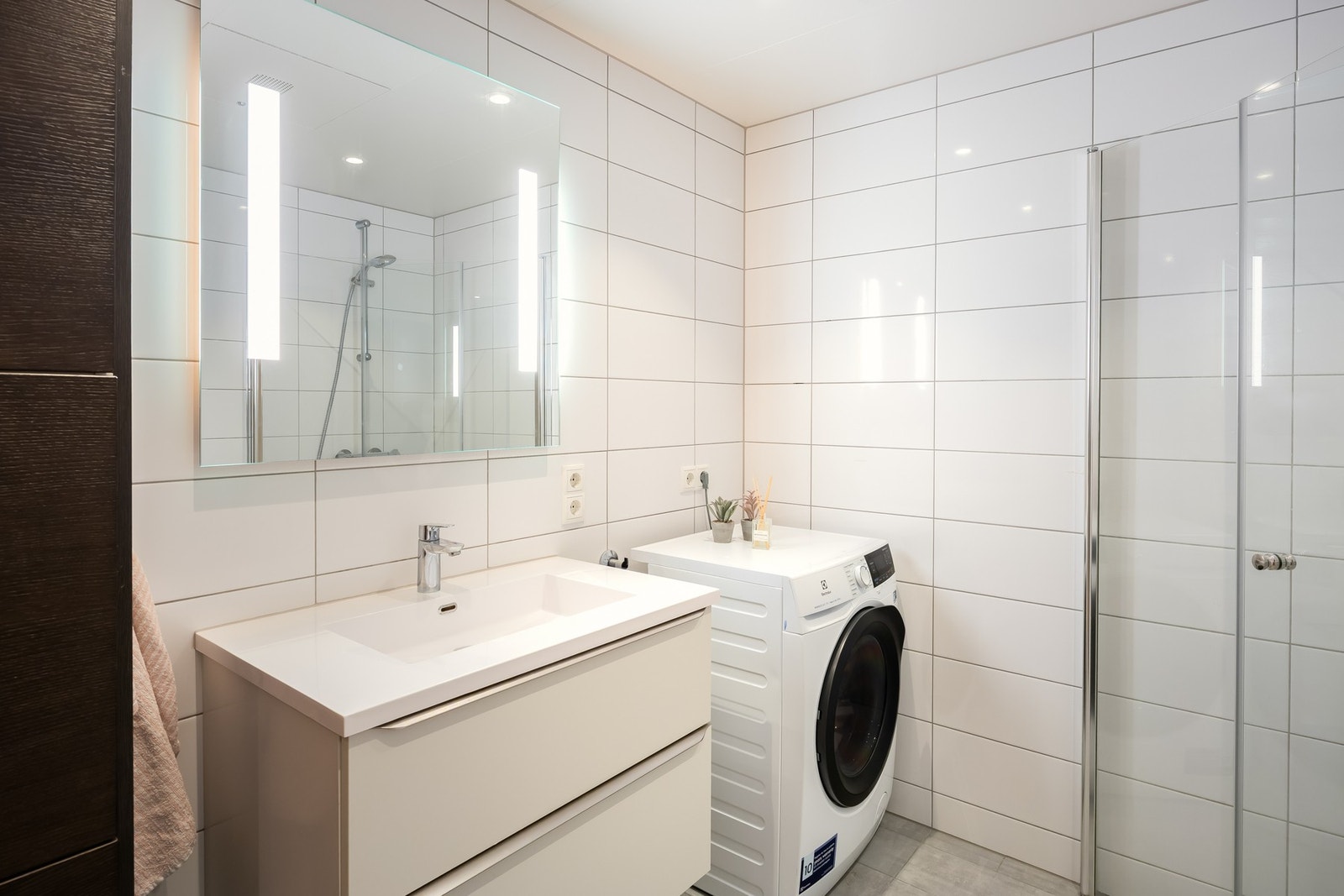 Romslig, helfliset bad på 5 kvm. Badet er utstyrt med opplegg for vaskemaskin og innfelbare dusjdører. Galleribilde