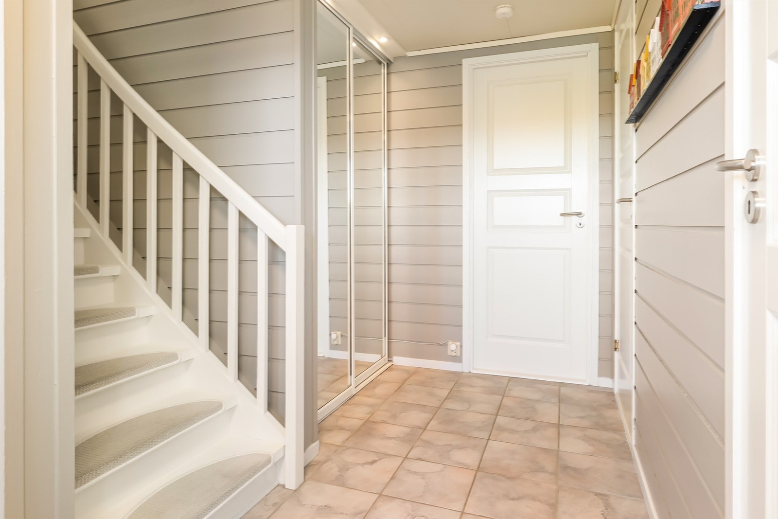 Entréen har flislagt gulv med varmekabler. En romslig skyvedørsgarderobe med speilfronter gir gode oppbevaringsmuligheter for yttertøy. Galleribilde