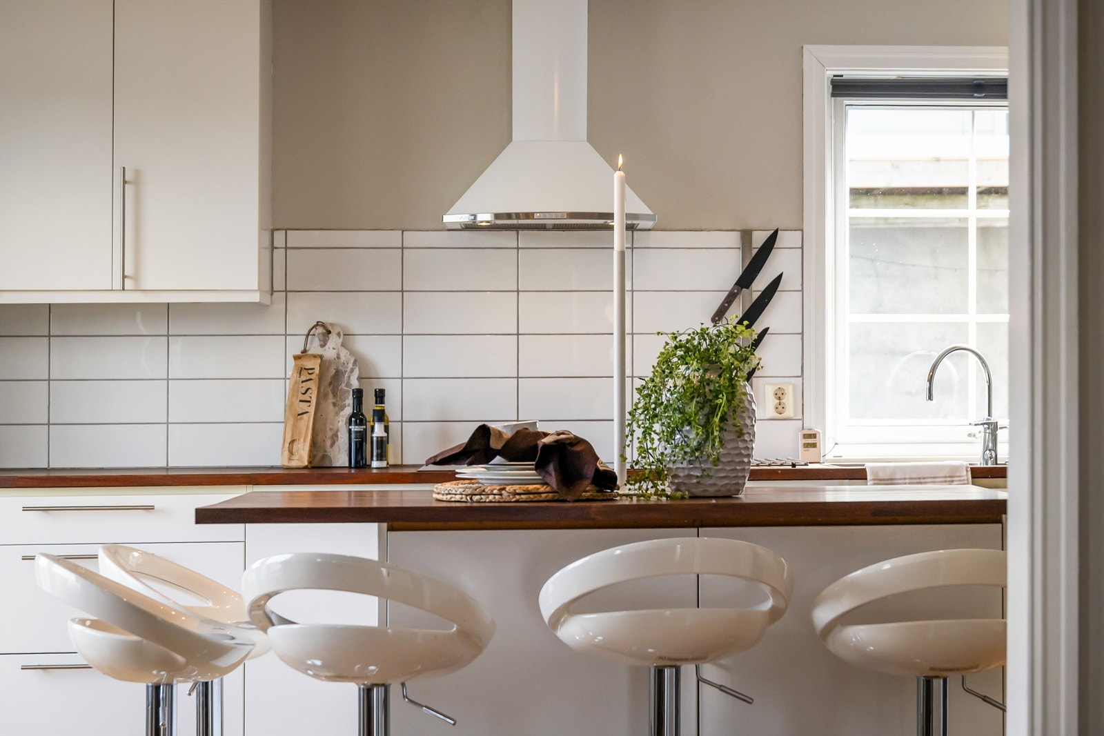 Kjøkkenøy med heltre benkeplate og plass til uformelle måltider. Det er fliser mellom benkeplate og overskap. Galleribilde