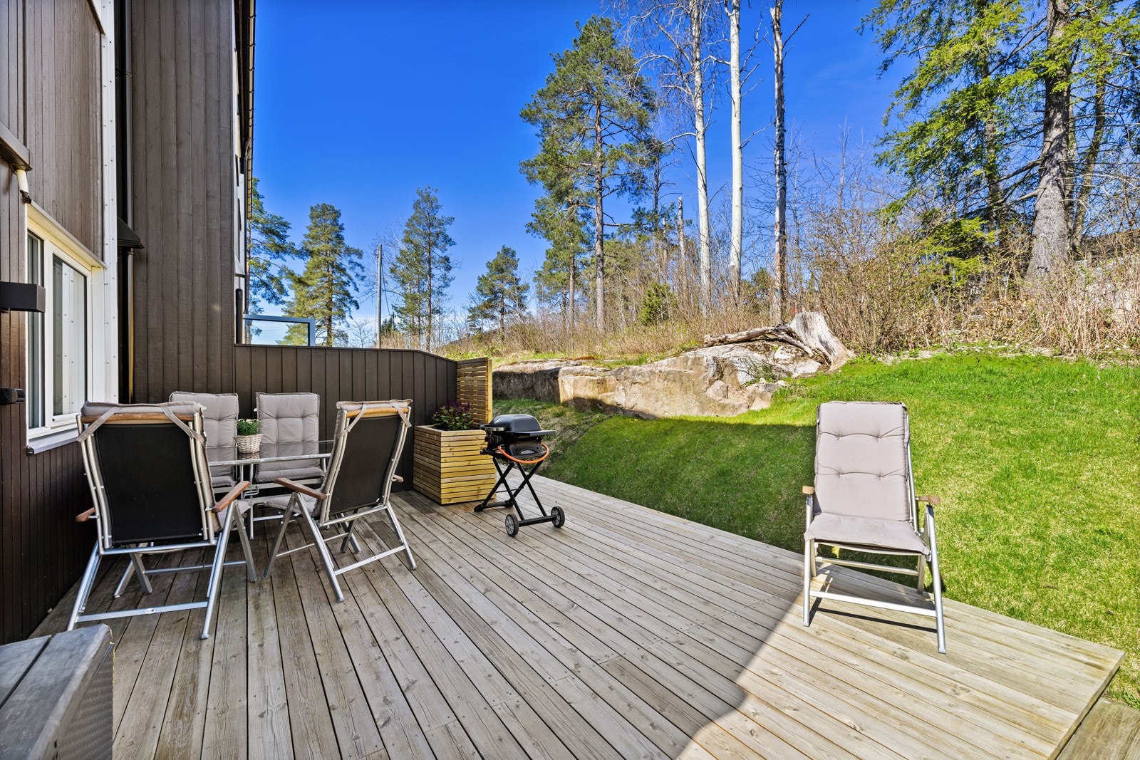 Solrik terrasse mot grønne omgivelser, med kort vei ut til plenen bak. Galleribilde