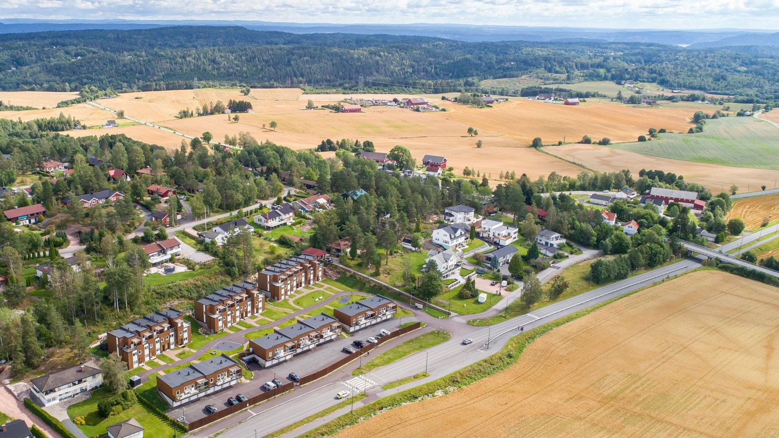Flyfoto av Brudeberget og Midtbygda, med jorder og skog tett på. Bilde tatt før beising av fasader Galleribilde