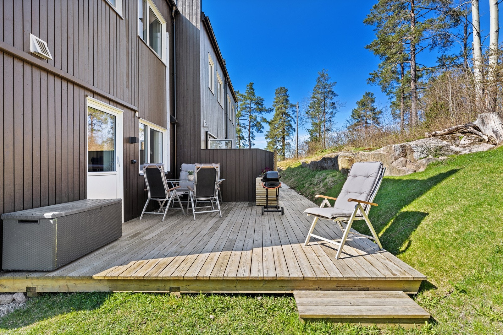 Uteplass på bakkeplan med plass til spisebord, grill og solstol rett utenfor stuen. Galleribilde