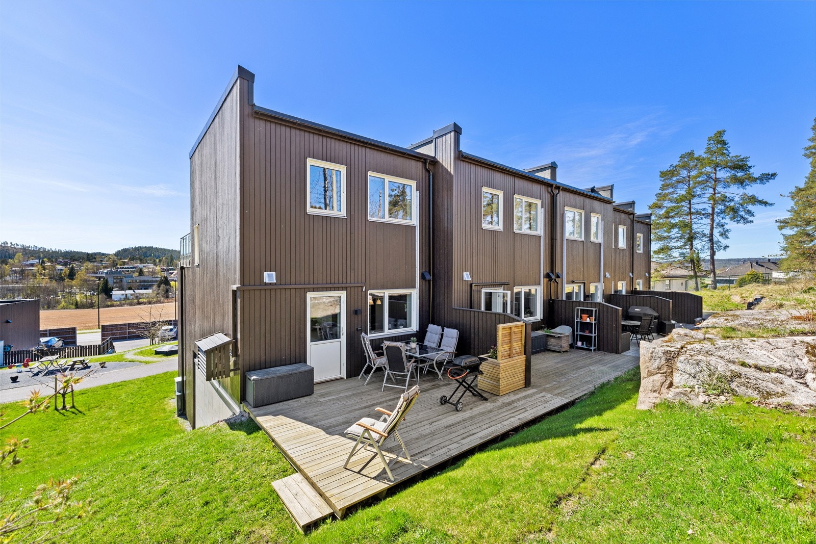 Boligen sett fra hagesiden, med uteplass på bakkeplan og inngang til terrasse. Galleribilde
