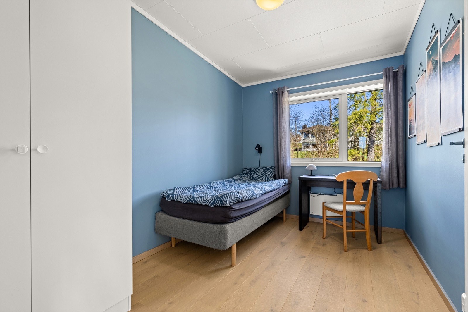Soverom med blågrønn vegg, gode lysforhold og plass til både seng og skrivebord. Galleribilde