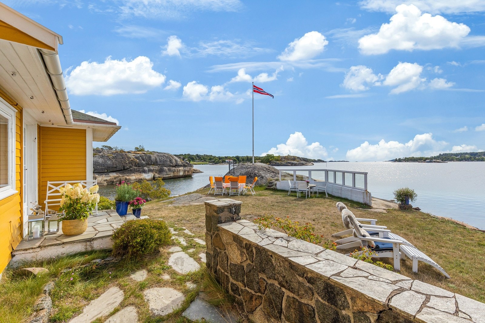 Uteplassen langs hytteveggen rammes inn med støpt, skiferdekket gjerde. Galleribilde