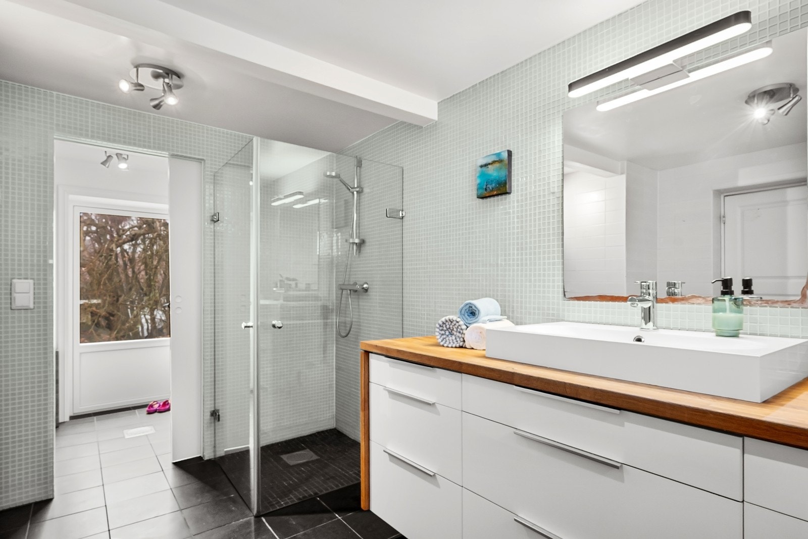Badet har også dusjnisje med innfellbare glassvegger. I tilknytning til rommet er det en praktisk vaskeromsdel. Galleribilde