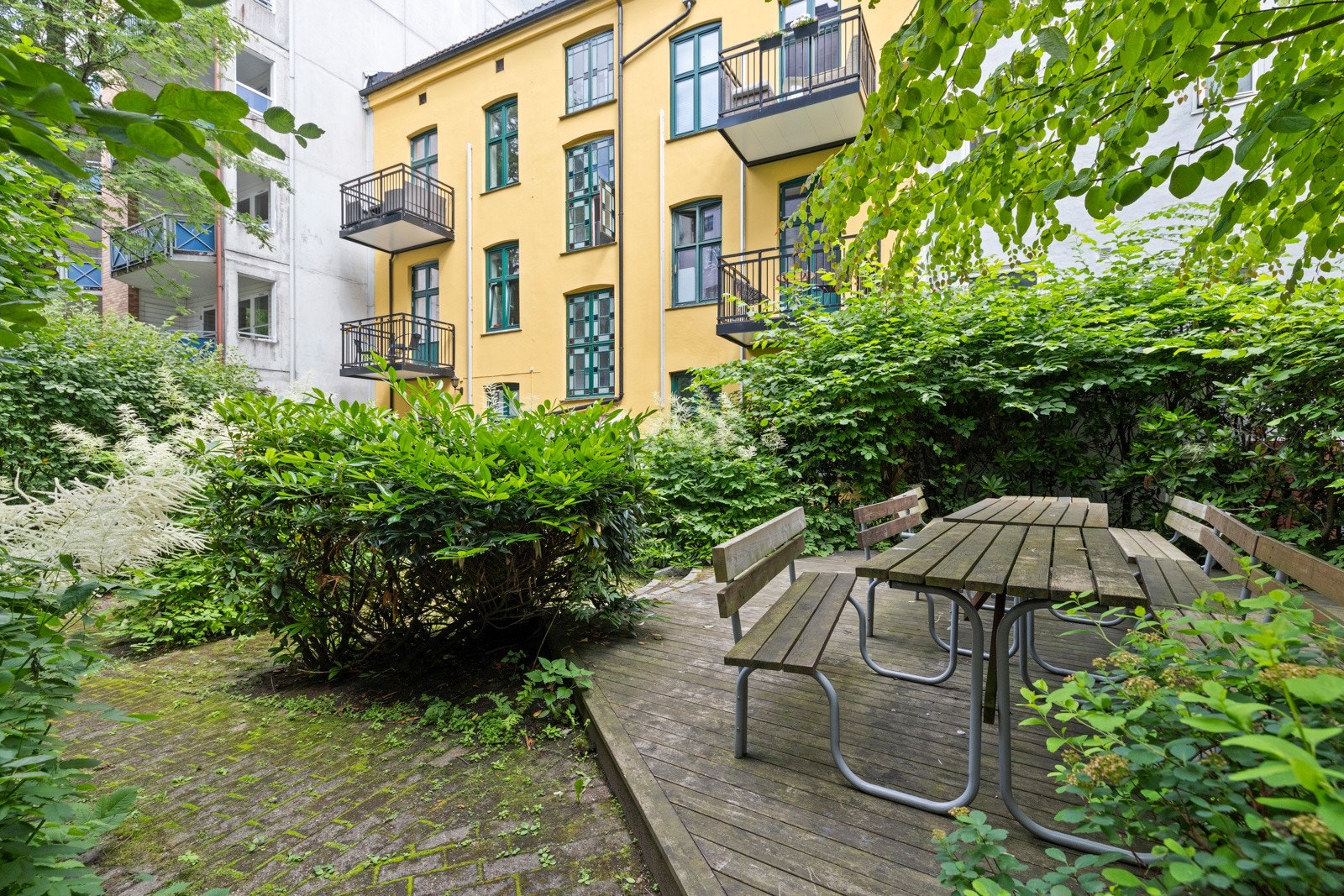 Bakgården er et flott, skjermet uterom med blomsterbed og store trær. Galleribilde