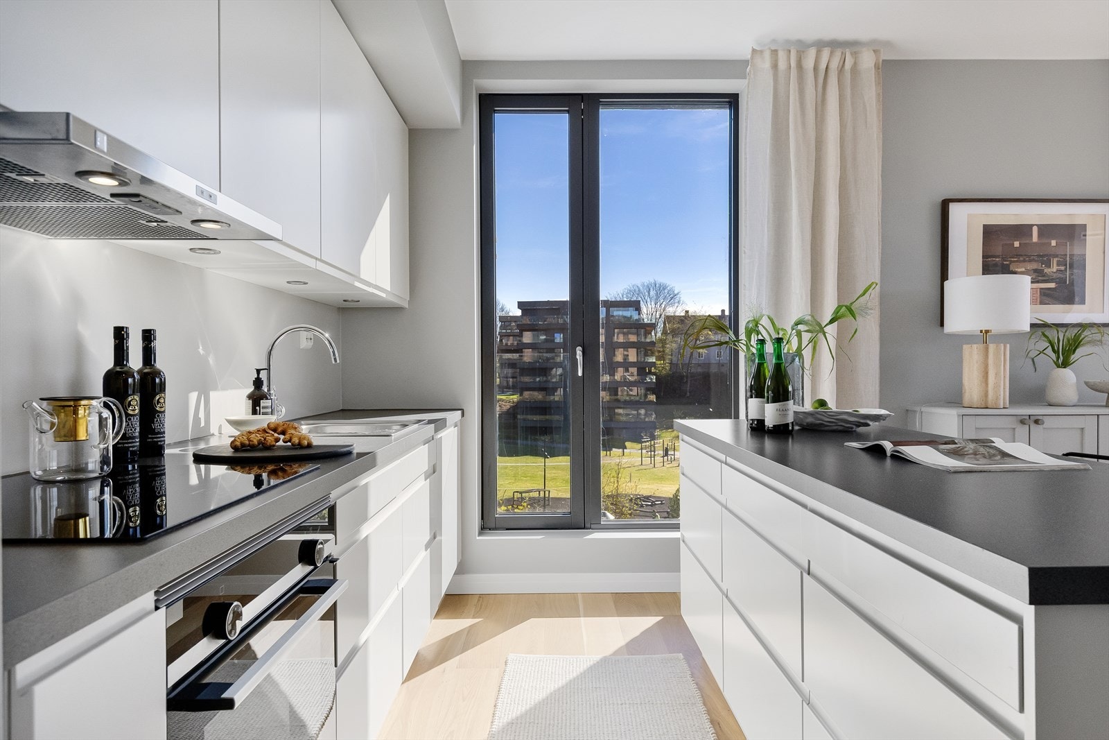 Pent, tilpasset Sigdal-kjøkken med slette fronter, belysning under overskap og laminat benkeplate. Kjøkkenøy i tilsvarende utførelse. Galleribilde