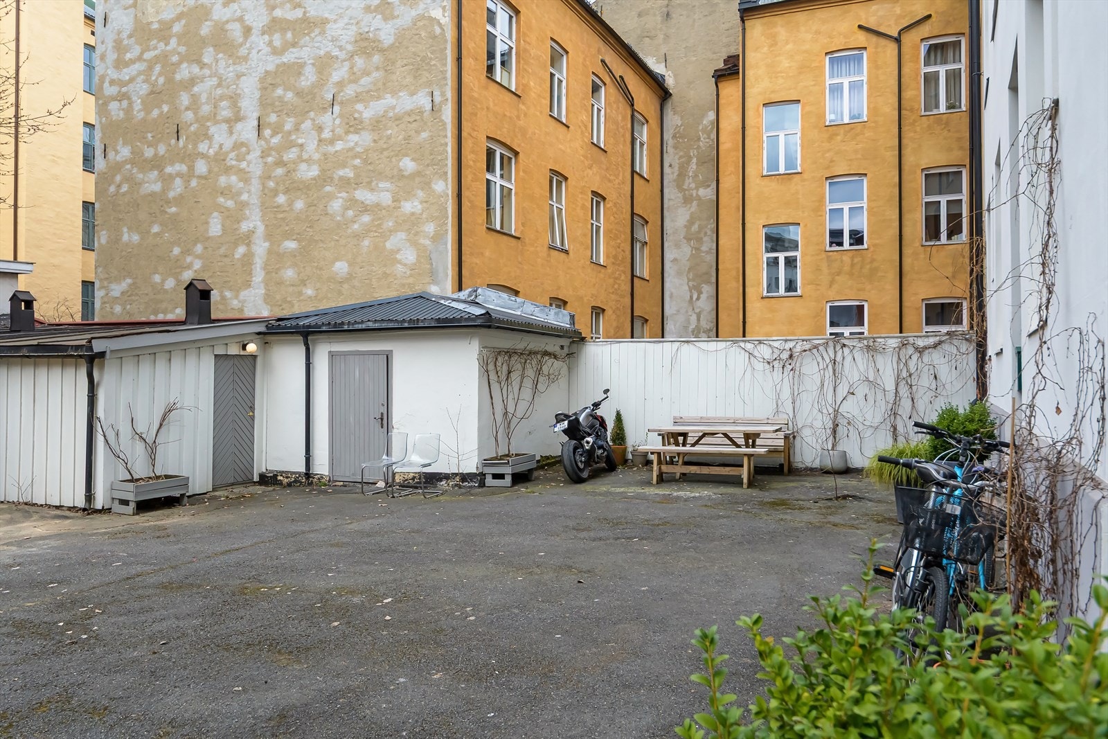 Bakgården er stor med sittebenker og beplantning Galleribilde