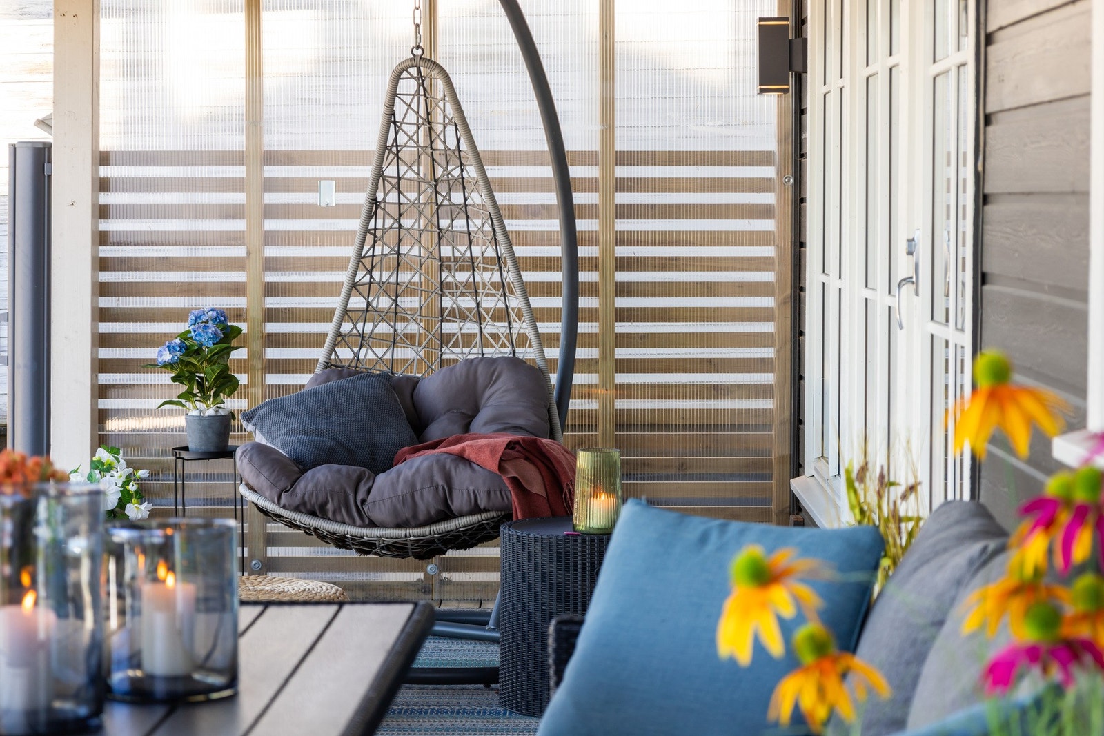 Koselig og stilfull uteplass med hengestol, myke puter, levende lys og blomster. Perfekt for avslapning på terrassen. Galleribilde