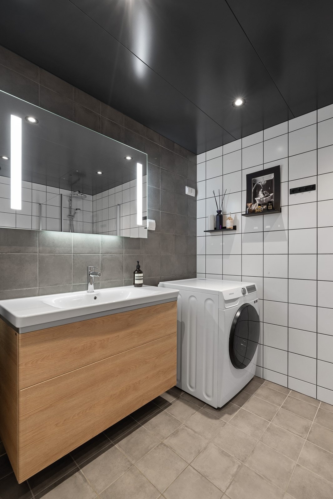 Badet er innredet med vegghengt toalett og en moderne baderomsinnredning med lysspeil Galleribilde