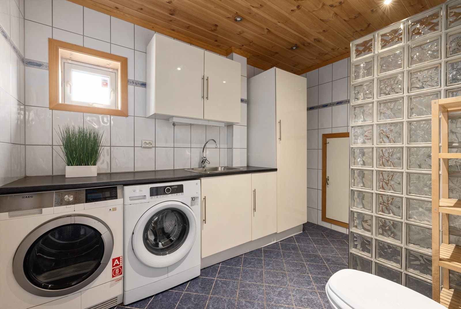 Badet i underetasjen er kombinert bad og vaskerom, og har fliser på vegger og gulv Galleribilde