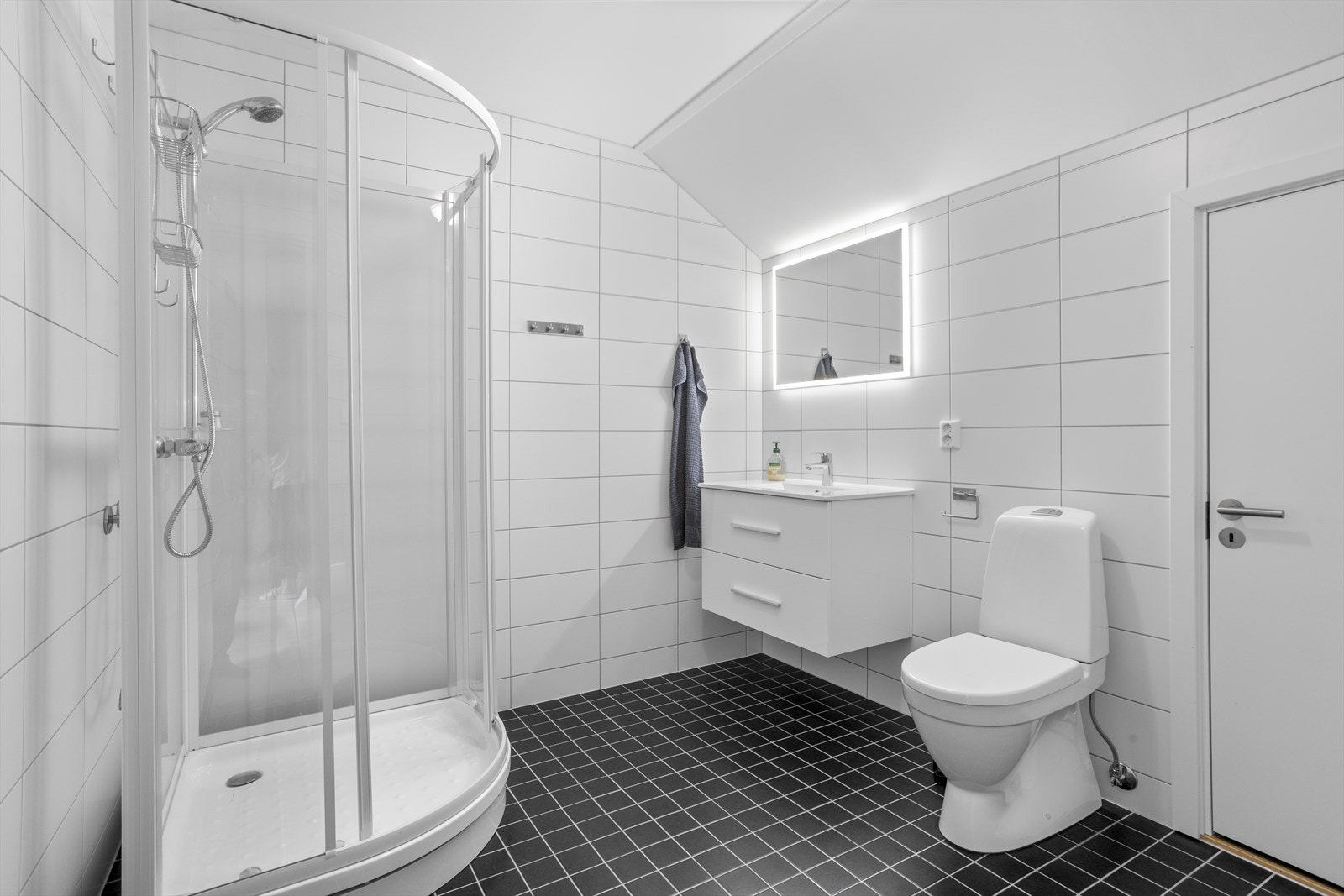 Stilrent bad med flislagte overflater, gulvvarme og speil med integrert belysning. Galleribilde