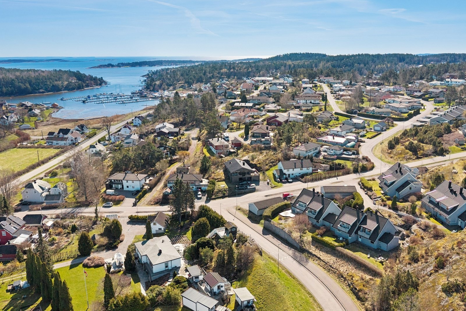 Dronefoto av bolig og nærområdet. Her bor du i et veletablert og familievennlig område med kort gangavstand til barnehager, skoler og dagligvarebutikk, en perfekt kombinasjon av trygghet og bekvemmelighet. Galleribilde