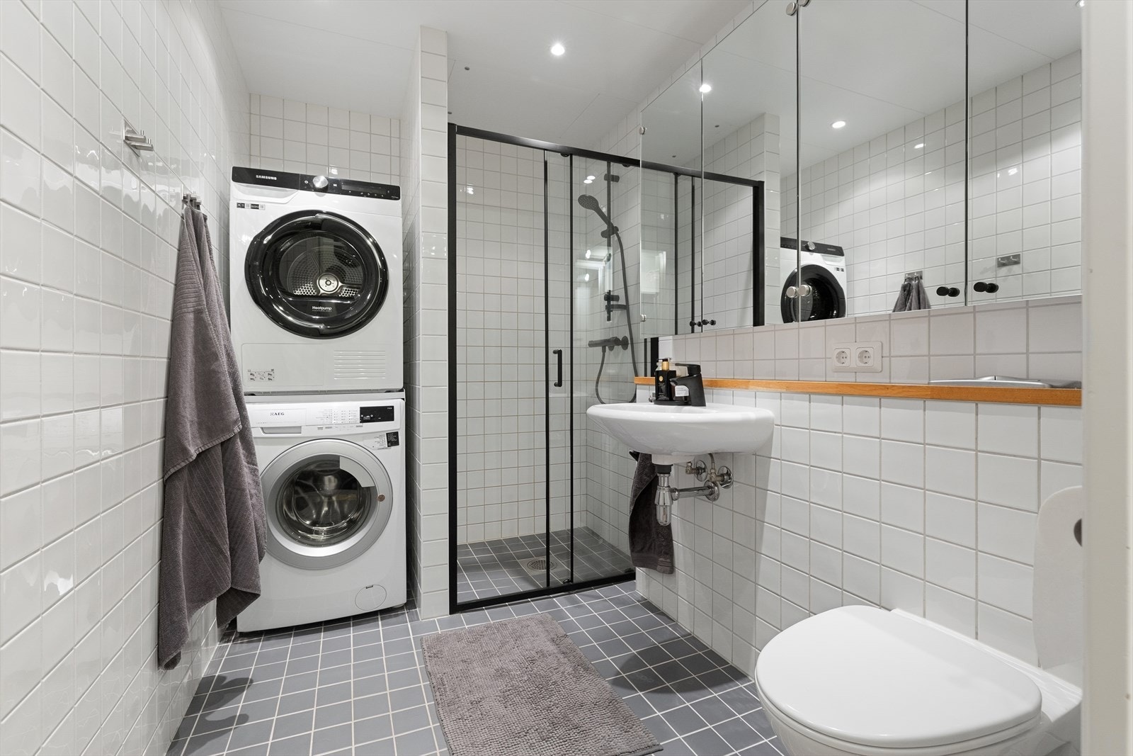 Romslig og tidløst bad med flislagte overflater, elektrisk gulvvarme og downlights i himling. Det er opplegg for vaskemaskin. Galleribilde