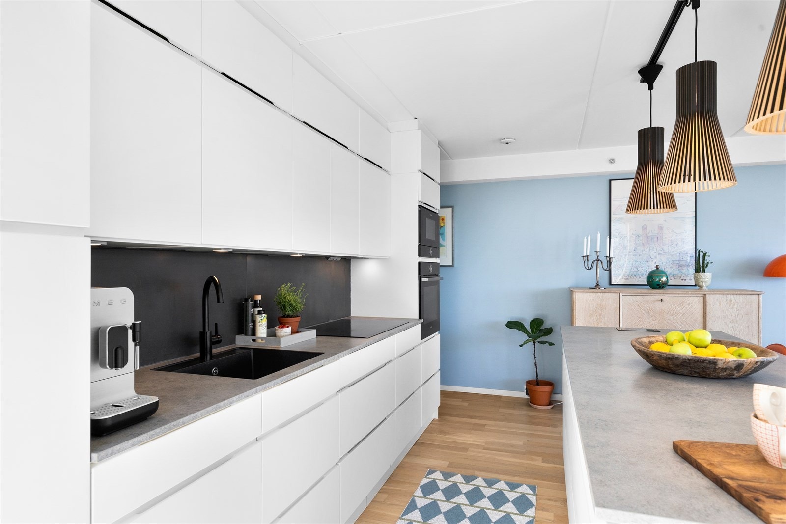 Innredningen har glatte fronter og laminat benkeplate med nedfelt kum og ettgreps blandebatteri, samt fliser mellom overskap og benkeplate som gir et helhetlig og tidsriktig uttrykk. Galleribilde