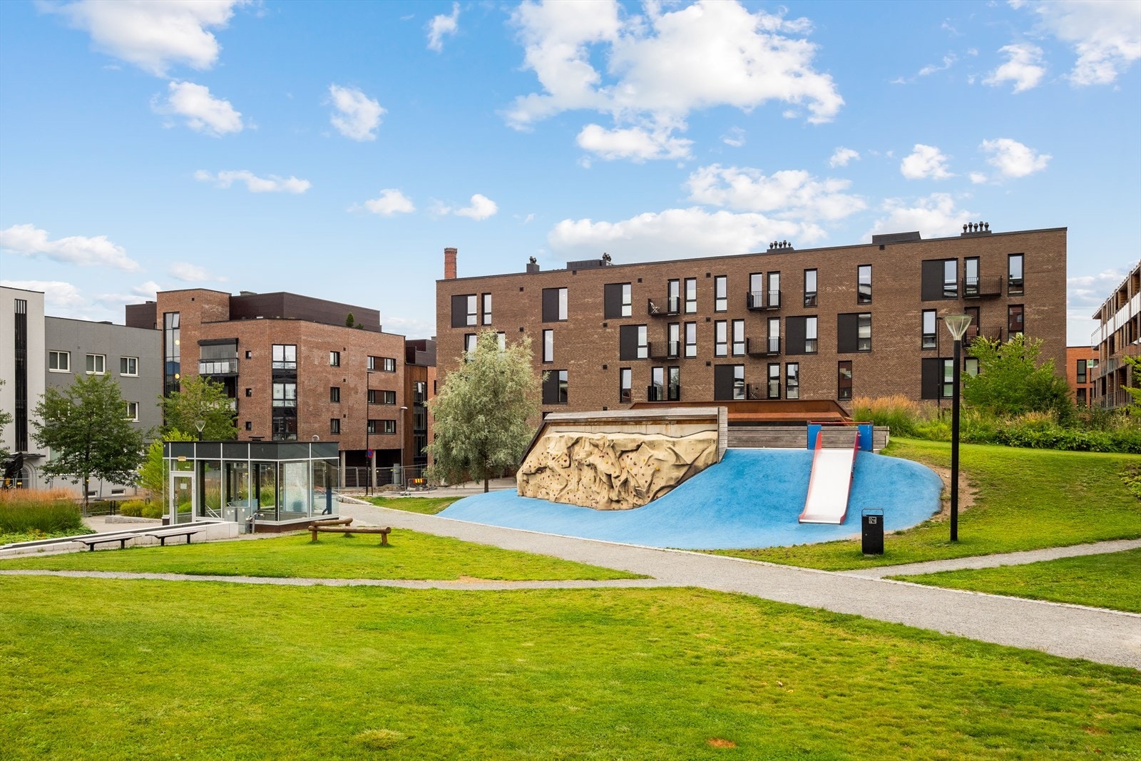 Grønt og trivelig uteområde med lekeplass i umiddelbar nærhet - perfekt for barnefamilier og aktive dager utendørs. Galleribilde