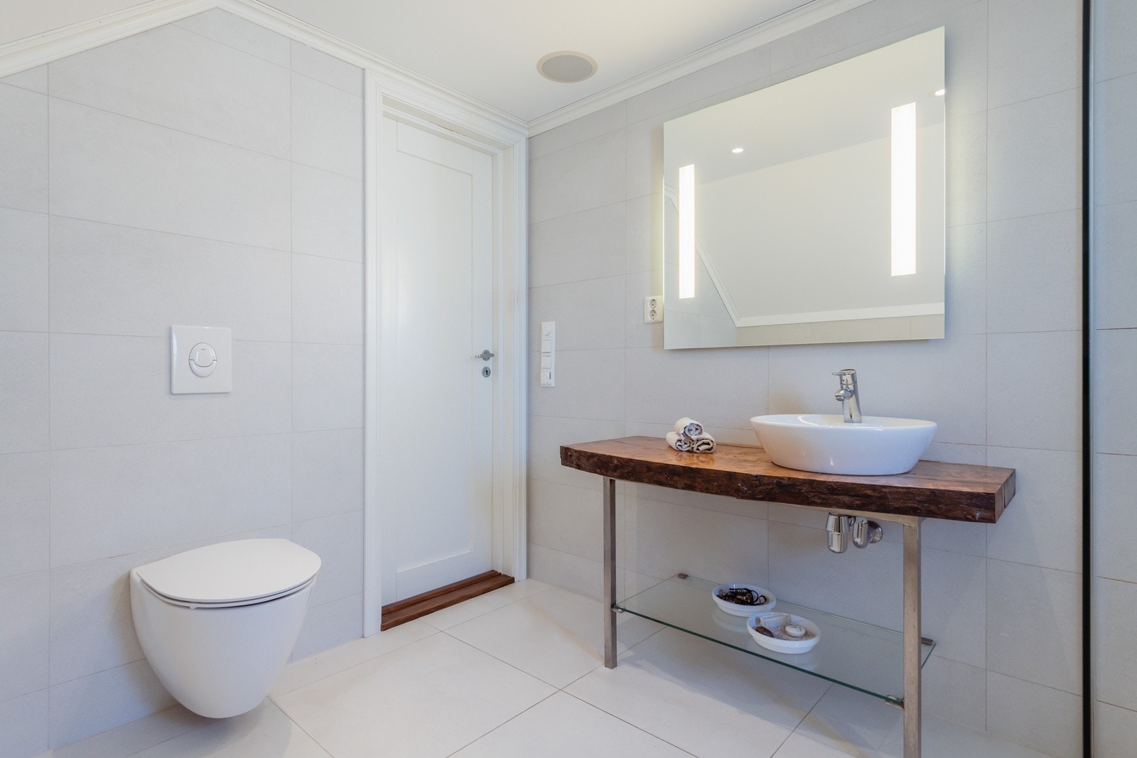 Badet er innredet med vegghengt toalett og en servant på en benkeplate av heltre. Galleribilde
