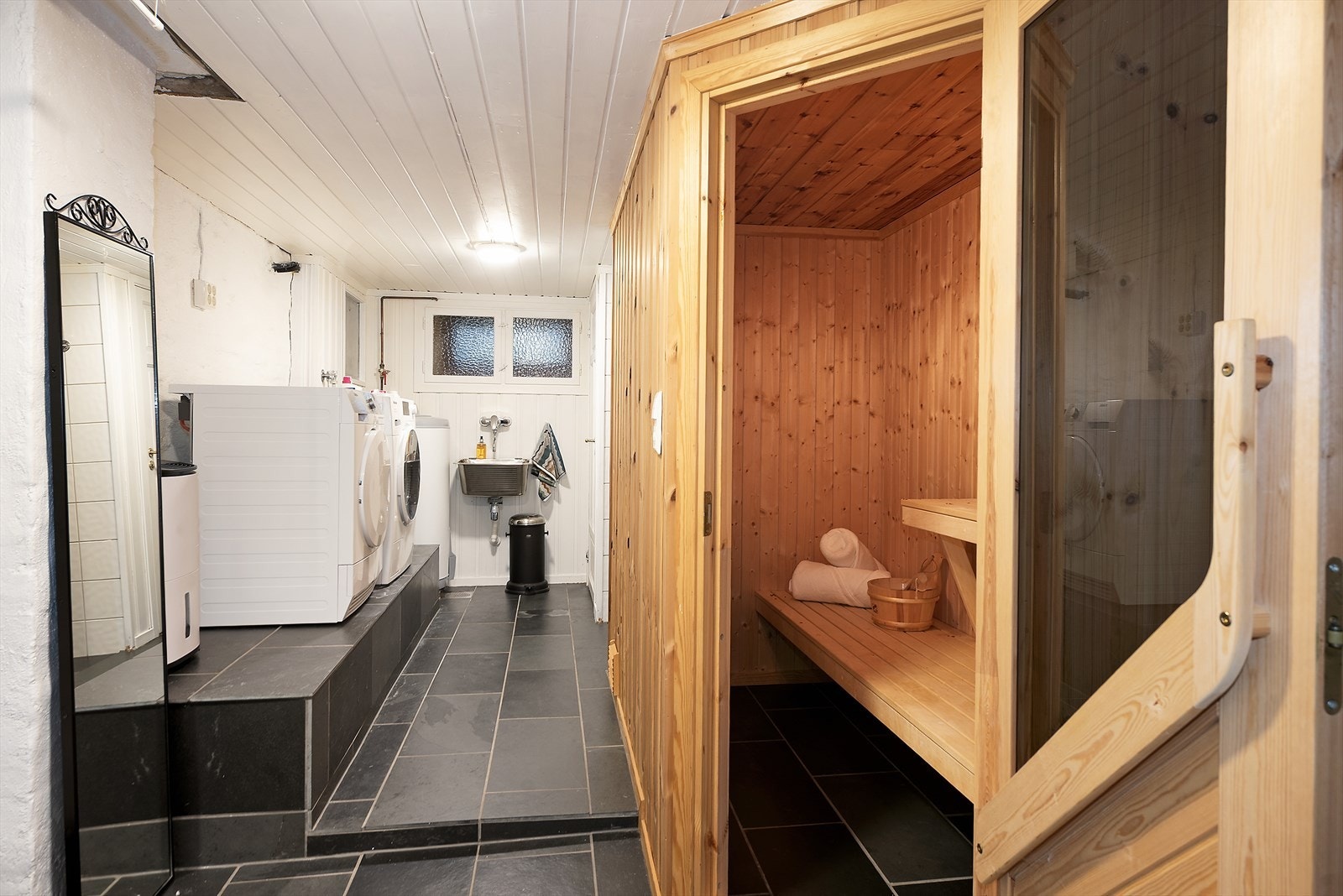 Kombinert vaskerom og velværeområde, med badstue. Et svært anvendelig tilleggsrom som gir boligen både komfort, funksjon og en ekstra luksusdimensjon. Galleribilde