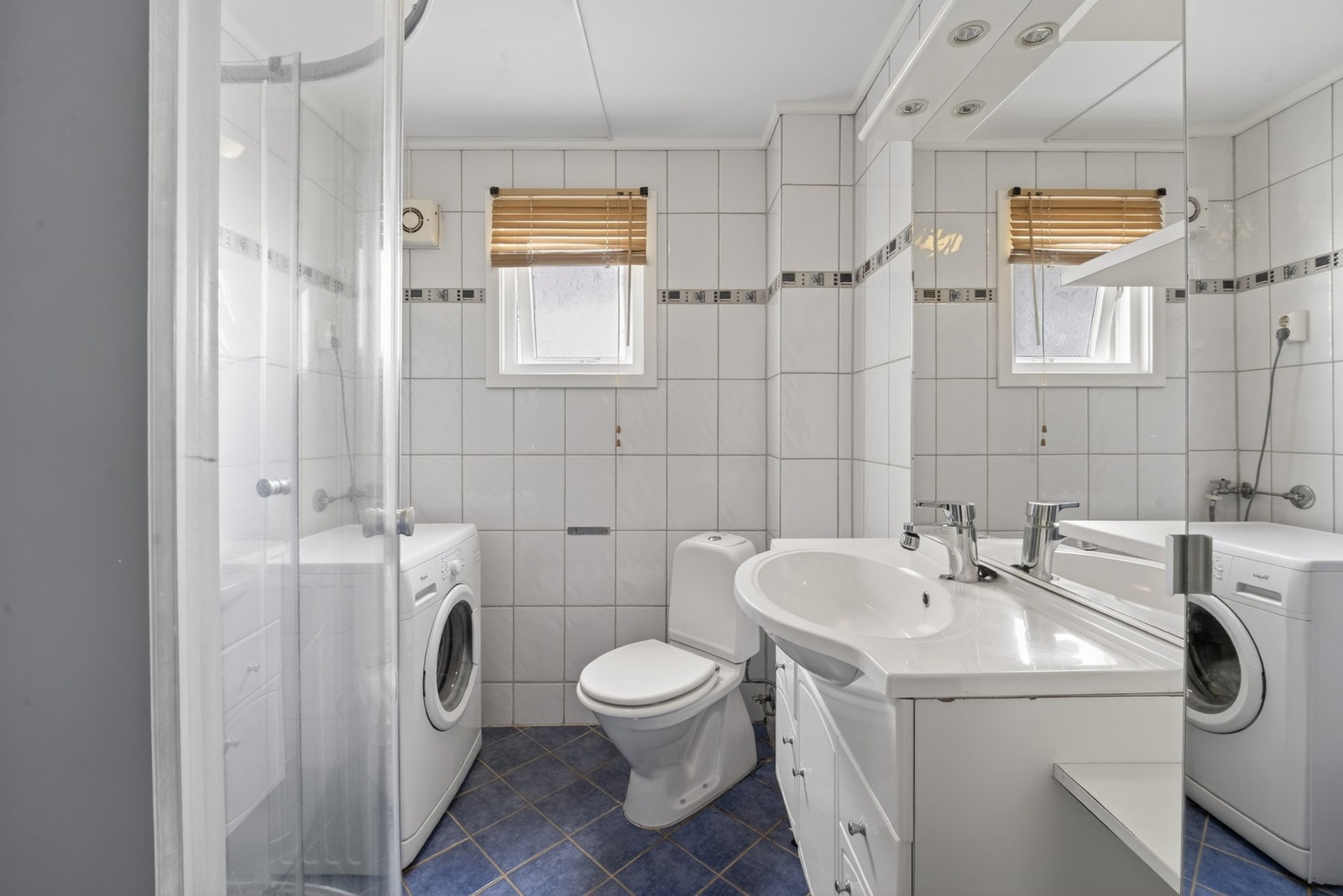 Badet er flislagt og inneholder dusjkabinett, servantinnredning, toalett og opplegg for vaskemaskin. Galleribilde