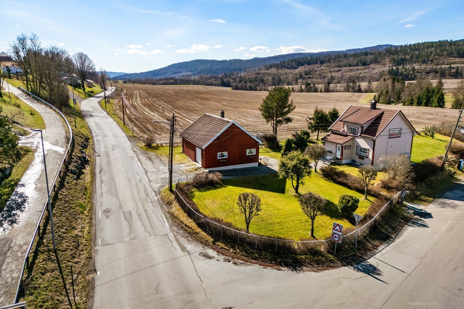 En klassisk enebolig fra 1936 med en stor, separat uthusbygning, beliggende på en tilnærmet flat tomt i landlige omgivelser.
Foto: Haiman Askari Galleribilde