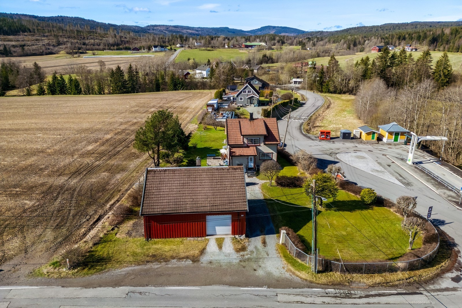 Gruset gårdsplass med god plass til parkering foran både boligen og uthuset. Galleribilde